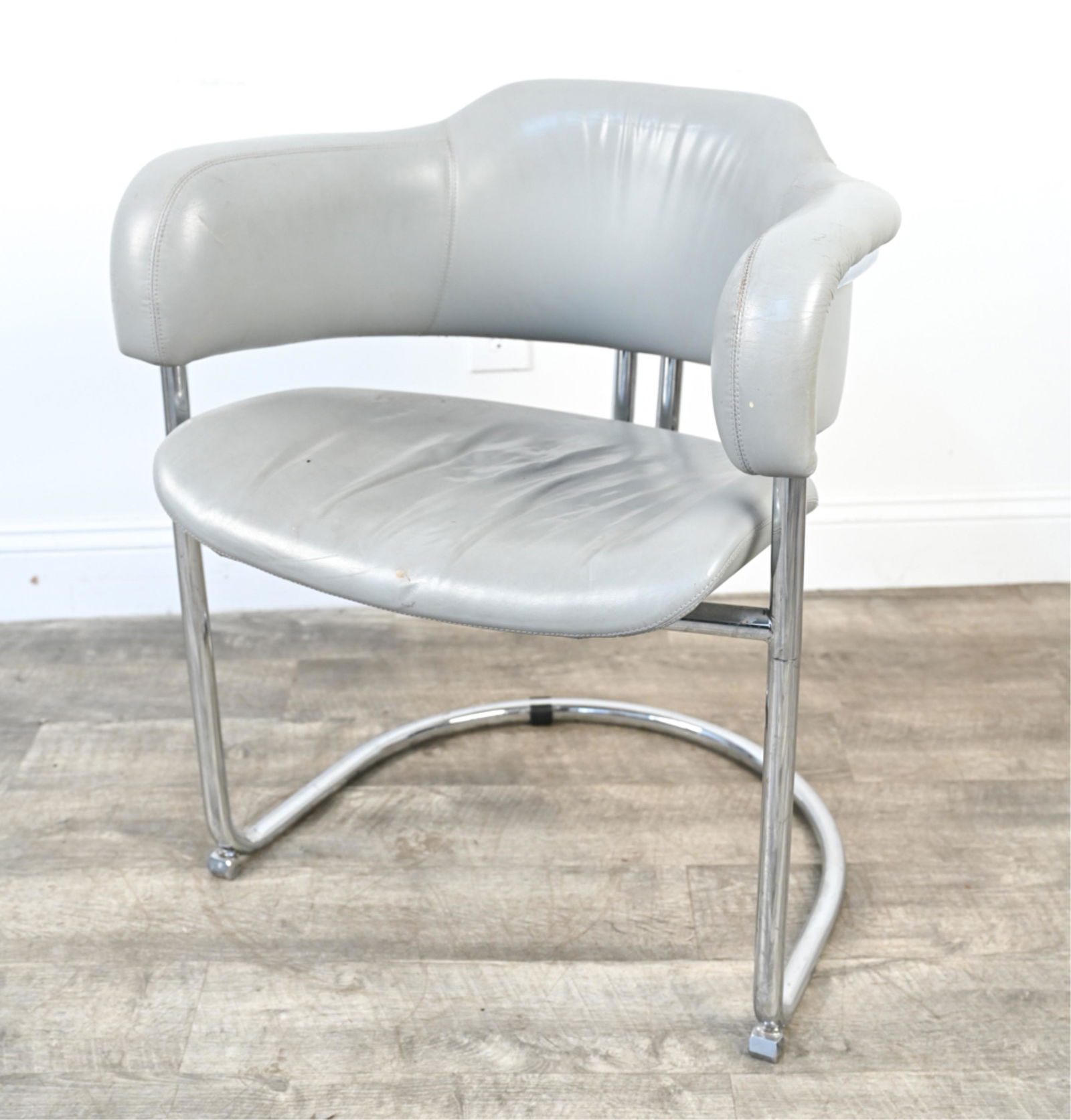 BAUHAUS STYLE TUBULAR CHROME CANTILEVER CHAIR: Barrel-back armchair in tubular chrome and gray leatherette, in they style of Hans and Wassili Luckhardt or Anton Lorenz; c. 1960's. Dimensions: H 29" x W 25" x D 21" x SH 17.5" Condition: Upholstery