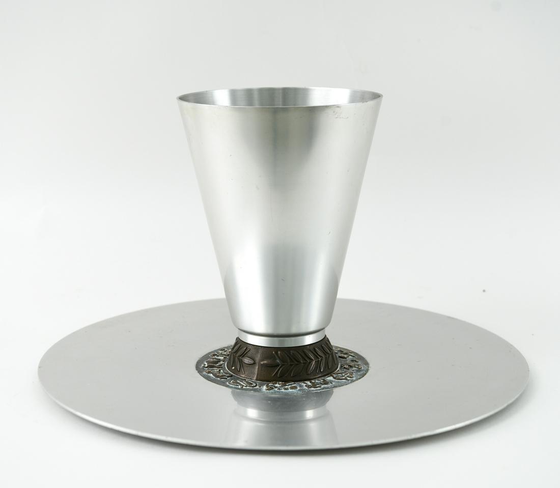 KENSINGTON MODERN ALUMINUM CHARGER & VASE: Charger with brass zodiac inlay and vase with brass base. Dimensions: (Charger) Dia. 18" Condition: Various surface scratches and scrapes. Wear consistent with age and use.