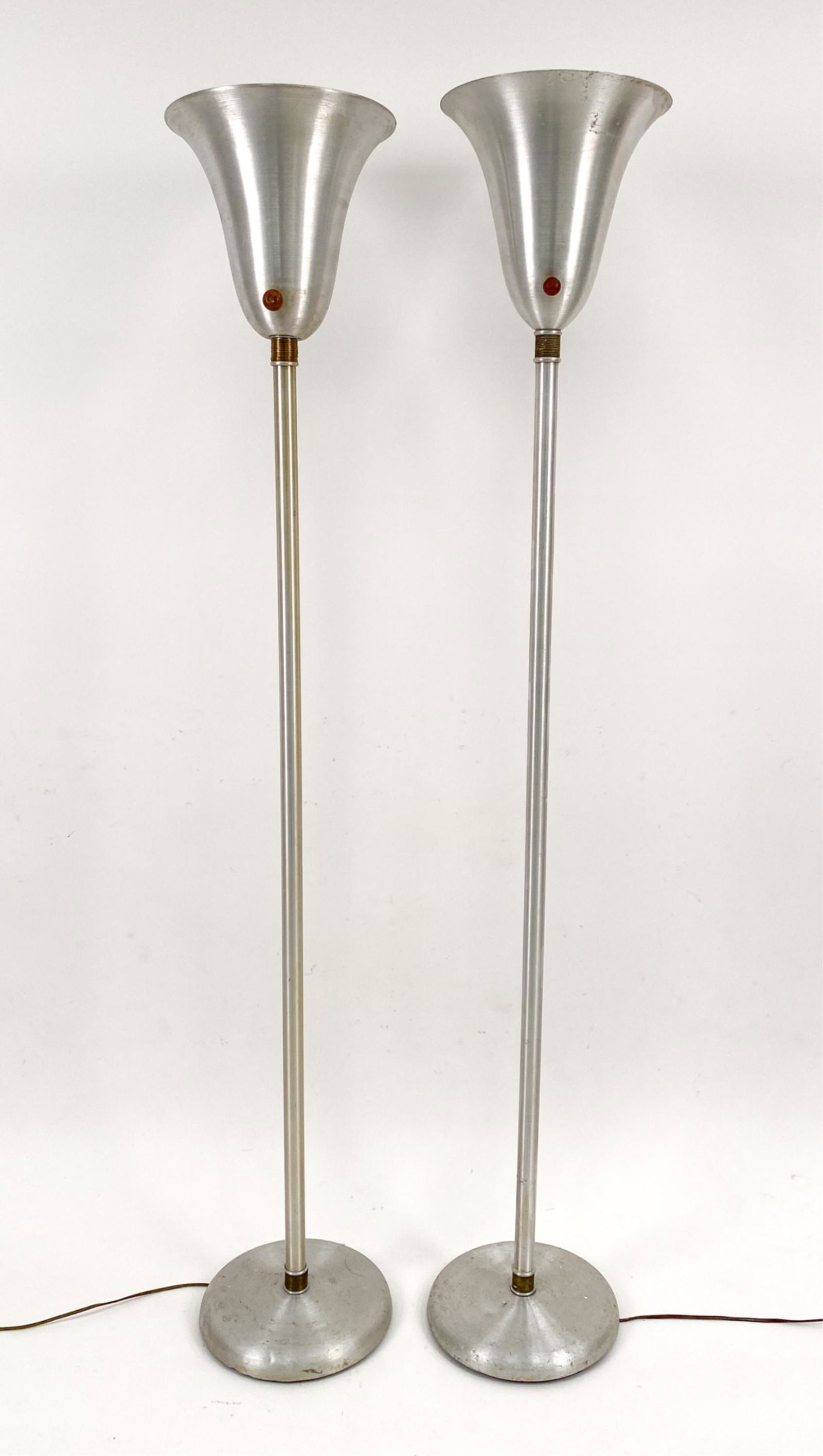 PAIR RUSSEL WRIGHT SPUN ALUMINUM FLOOR LAMPS: (2) Russel Wright spun aluminum and brass torchiere floor lamps. Dimensions: H 65" x Dia. 11" Condition: Surface wear, dings and scratches consistent with age and use. One lamp is missing original woo
