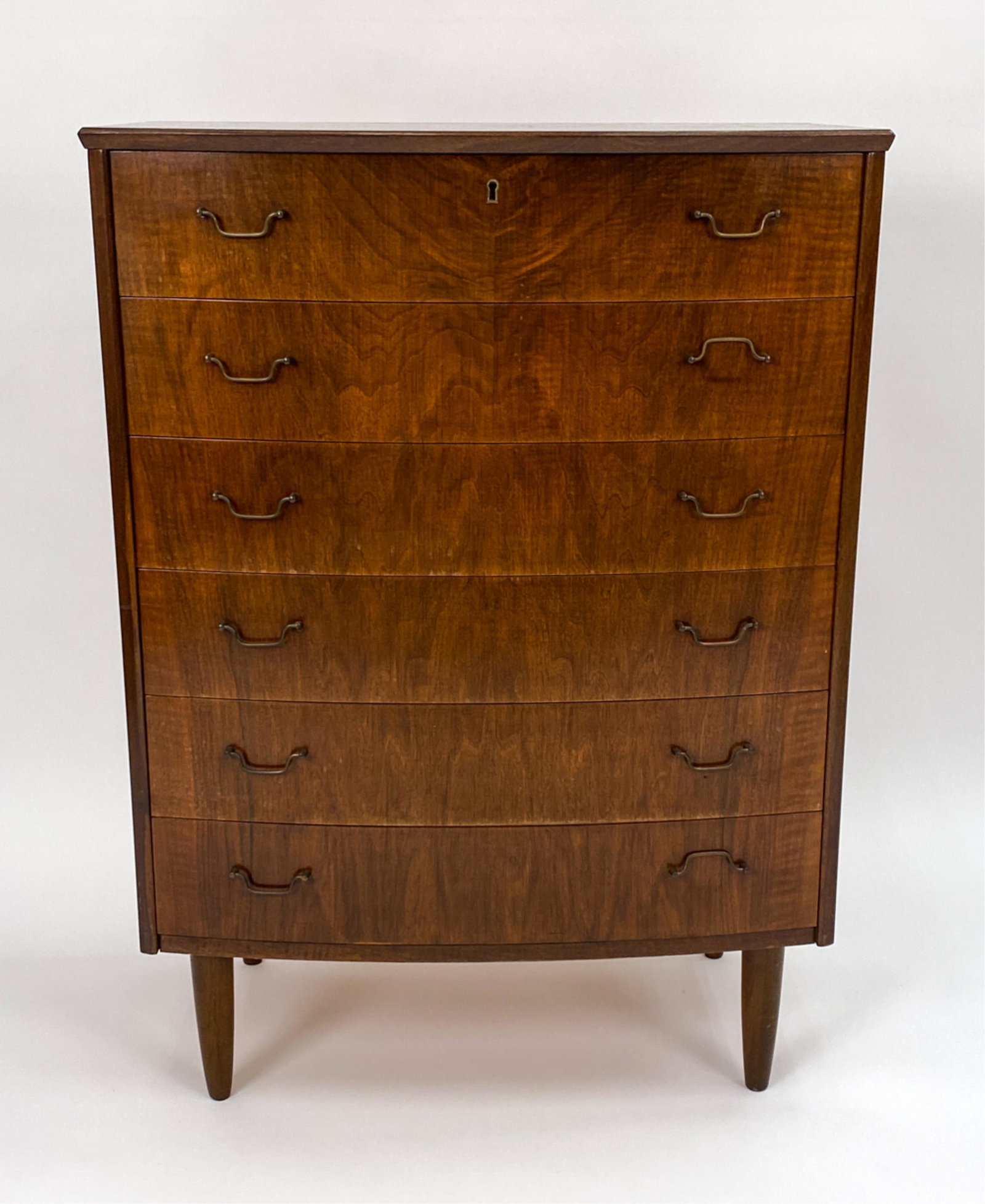 DANISH MID-CENTURY NUT WOOD CHEST OF DRAWERS: Danish 6-drawer chest with curved front, delicate brass bale handles. c. 1950's. Dovetailed drawer joints. Dimensions: H 42" x W 30.5" x D 17.5" Condition: Wear consistent with age and use including s