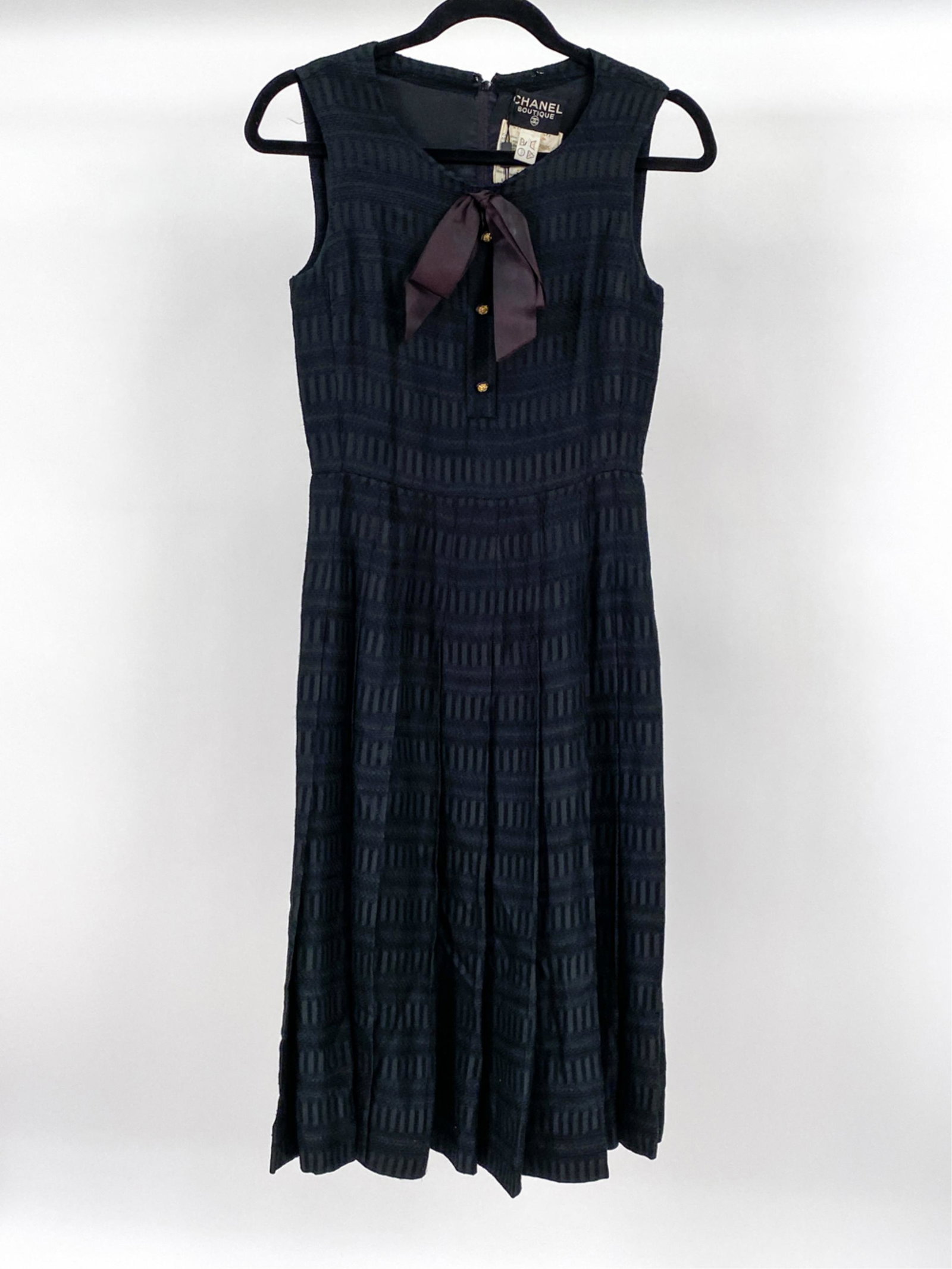 1980'S CHANEL COUTURE SILK KNIFE-PLEAT DRESS: Exquisite and rare Chanel dress in embroidered silk with flared knife pleat skirt, lion's head buttons and ribbon bow. Size FR 26. Condition: In very good vintage condition overall; a couple tiny pull