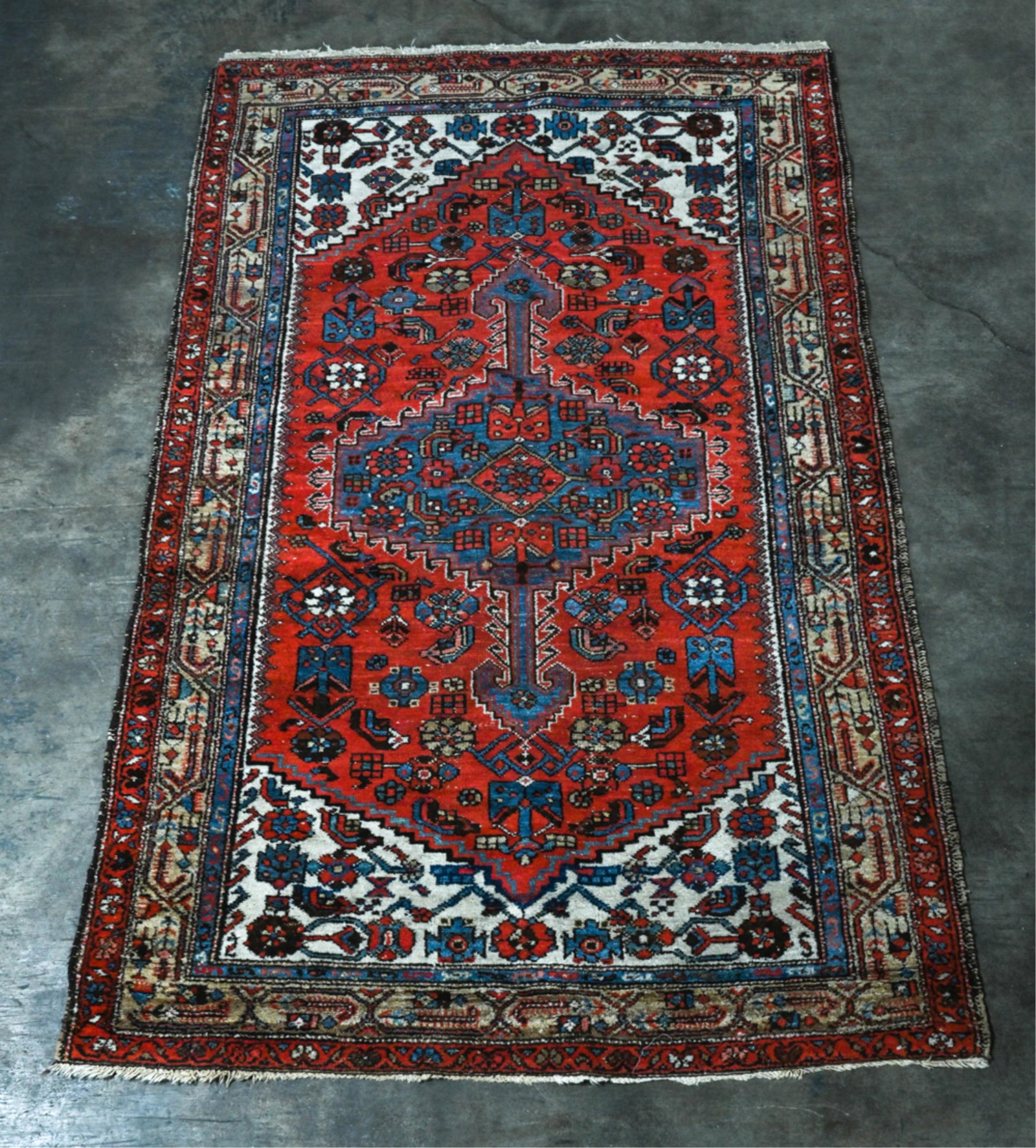 SEMI-ANTIQUE HAND-KNOTTED THROW RUG: Dimensions: L 79" x W 49" Condition: Reinforcements and repairs to fringe and bound edges; some light sun fading and rubbing to pile.