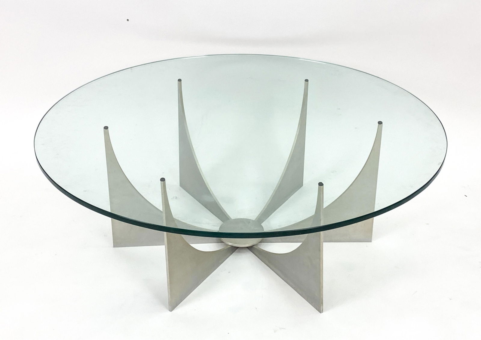 DONALD DRUMM MODERNIST COFFEE TABLE: Glass with cast aluminum base. Dimensions: H 15.5" x Dia 44" Condition: Minor wear. Small loss to one rubber bumper where glass meets base.