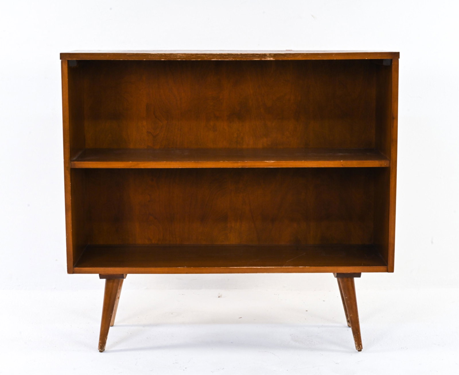 MANNER OF MCCOBB BOOKSHELF: Cabinet on tapered legs with two shelves. No labels. Dimensions: H 33.25" x W 36" x D 12" Condition: Extensive finish wear/finish loss to legs. Scattered scratches, nicks, dings, and marks. Some sun f