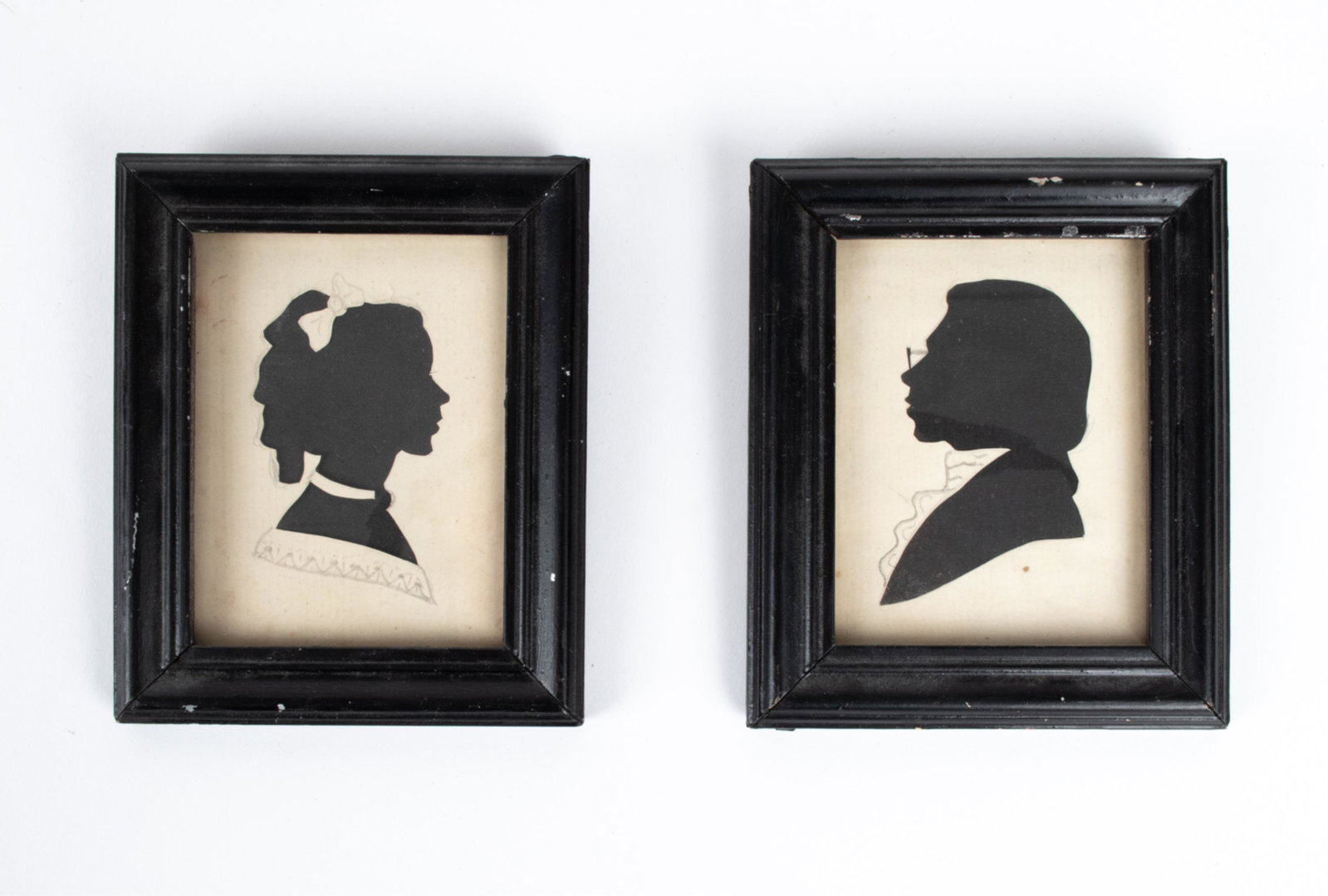 PAIR OF ANTIQUE DIMINUTIVE CUT PAPER SILHOUETTES: White cut paper and graphite over black ground. Apparently unsigned. Dimensions: (Frame) H 4.5" x W 3.75" Condition: Paper with light toning, a couple spots of browning/stray marks. Nicks and finish l