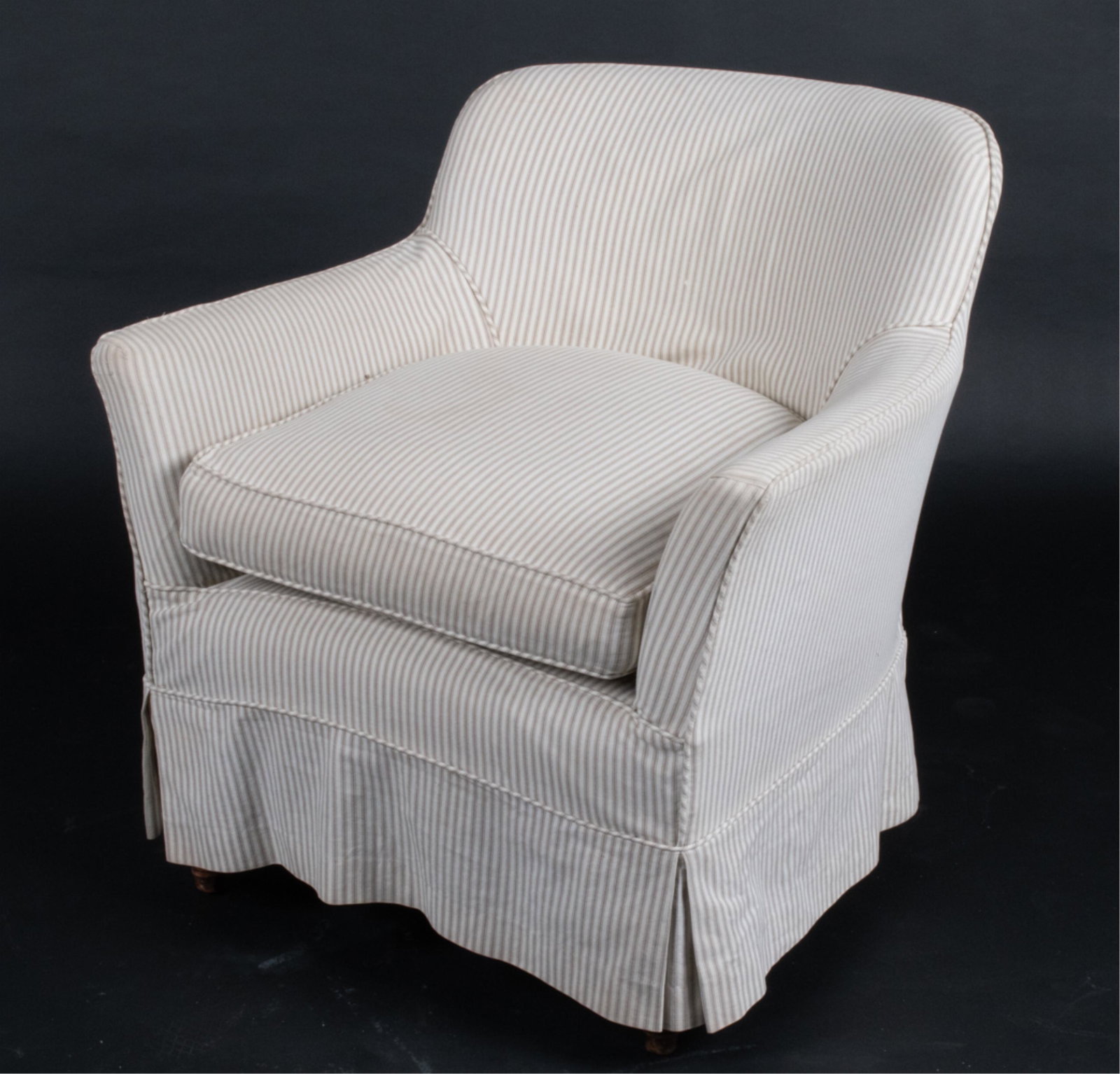 SLIP-COVERED STRIPED LOUNGE CHAIR: No apparent labels. Skirted slip cover and underneath fabric are the same pattern. Dimensions: H 31.5" x W 30" x D 25" x SH (incl. cushion) 19" Condition: Some soiling to fabric. Wooden legs with mode