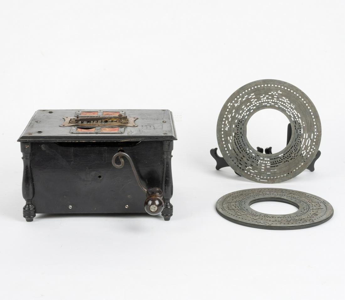 INTONA ORGANETTE EARLY DISC PLAYER W/ MEDIA: Stamped galvanized metal discs. Dimensions: H 6.5" x W 11" x D 9" Condition: Media loads and mechanism advances properly, however no sound is produced so bellows are likely damaged. Black paint rough,