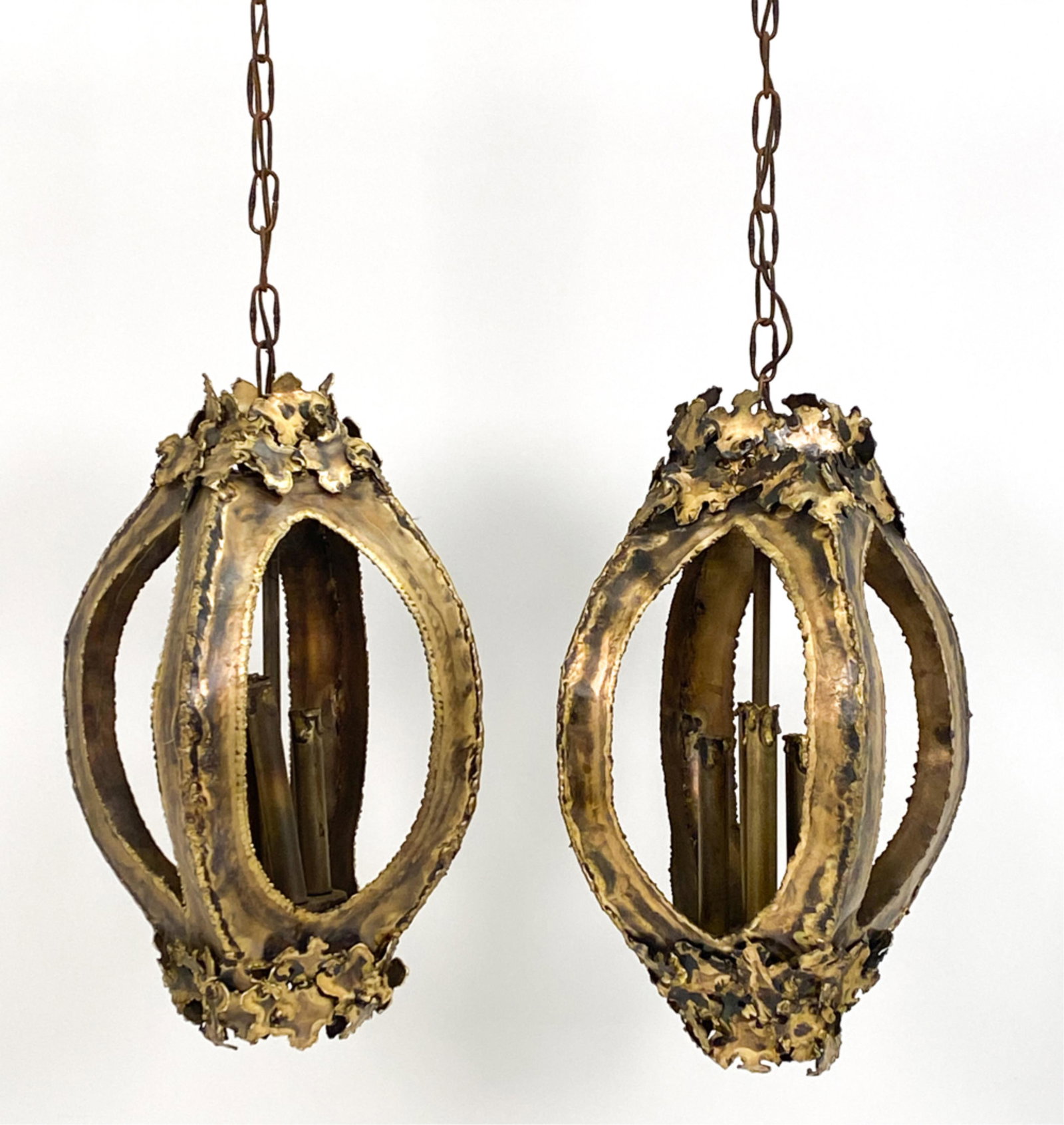 (2) TOM GREENE BRUTALIST BRASS HANGING LIGHTS: Great pair of Brutalist torch cut patinated brass hanging pendant lights designed by Tom Greene for Feldman Lighting Co. circa 1960s. Dimensions: H 19.5" x Dia 9.5" Condition: Rich patina. Tarnish con