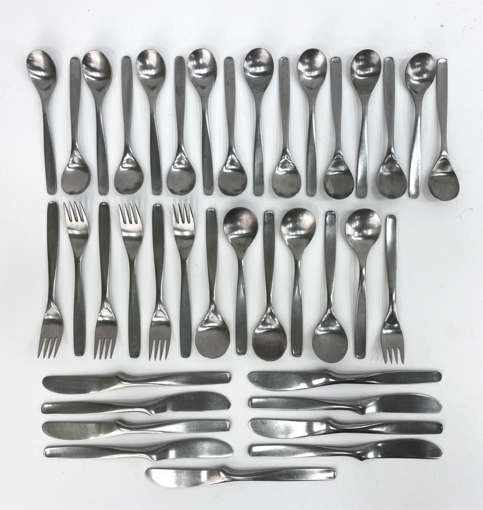 RUSSEL WRIGHT HULL PINCH STAINLESS FLATWARE: Including (6) larger forks, one smaller fork, (9) knives, (6) table spoons, and (16) teaspoons. Marked to handles. Dimensions: (Knife) L 8.75" Condition: Normal signs of age and use including surface