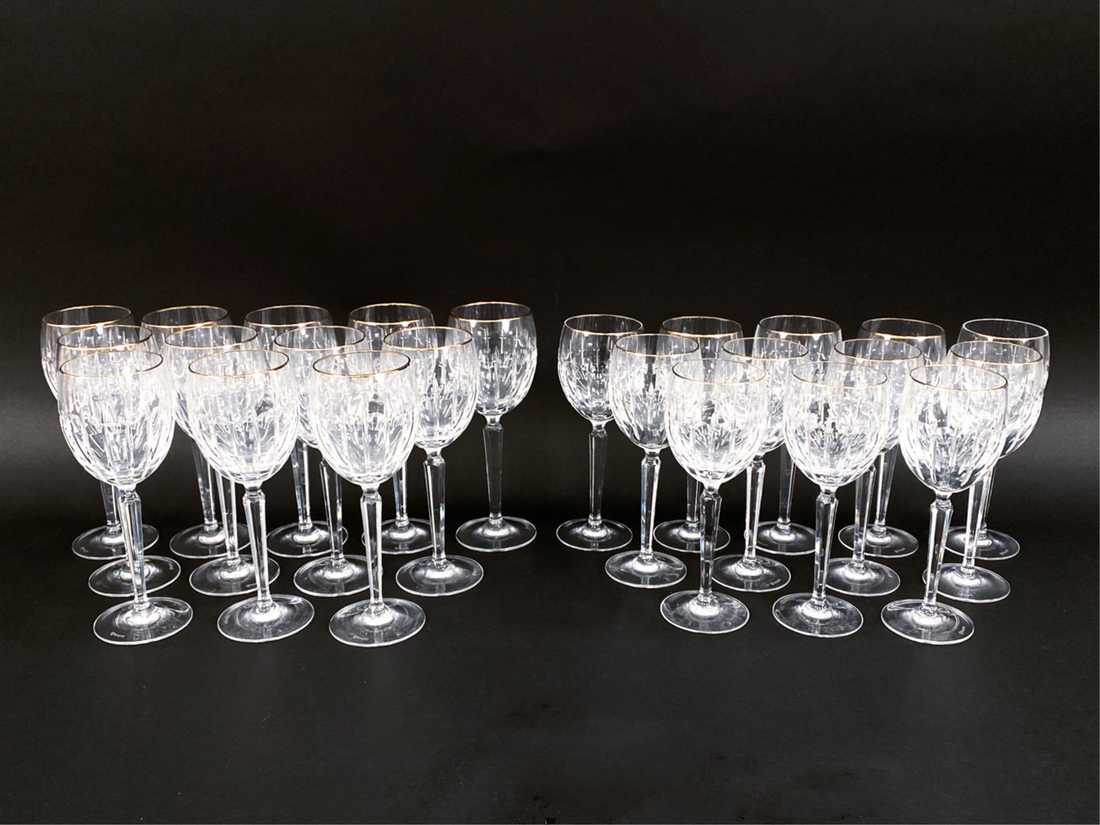 (24) WATERFORD CUT CRYSTAL GOBLETS: Gold-rimmed with fluted cuts. Marked underneath. (12) water glasses and (12) wine glasses. Dimensions: (Taller) H 9" x Dia. 3.25" Condition: Minor use wear.