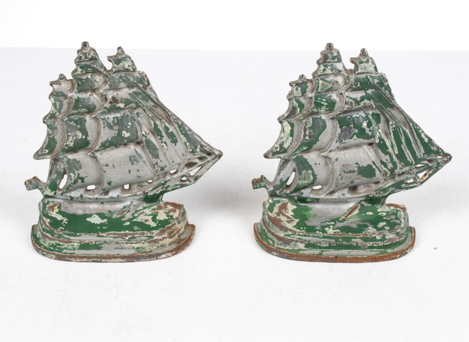 PAIR COLD-PAINTED CAST IRON GALLEON SHIP BOOKENDS: Bookends or doorstops. Dimensions: (Single) H 7" x W 7" x D 2" Condition: Repainted; distress to both paint finishes. Wear consistent with age.