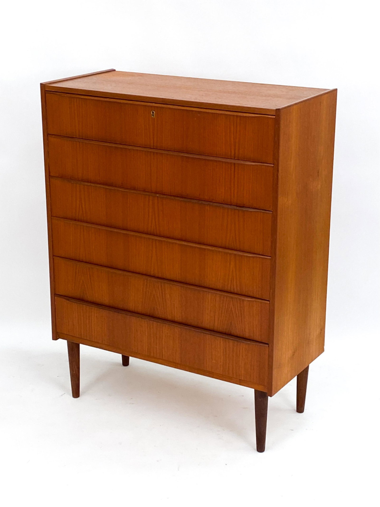 DANISH MID-CENTURY TEAK CHEST OF DRAWERS: Dovetailed drawer joints. c. 1960's. Lacking key. Unsigned. Tapered legs. Dimensions: H 45.5" x W 34.75" x D 16.5" Condition: Few light scattered scratches. Small losses to proper left side back edge.