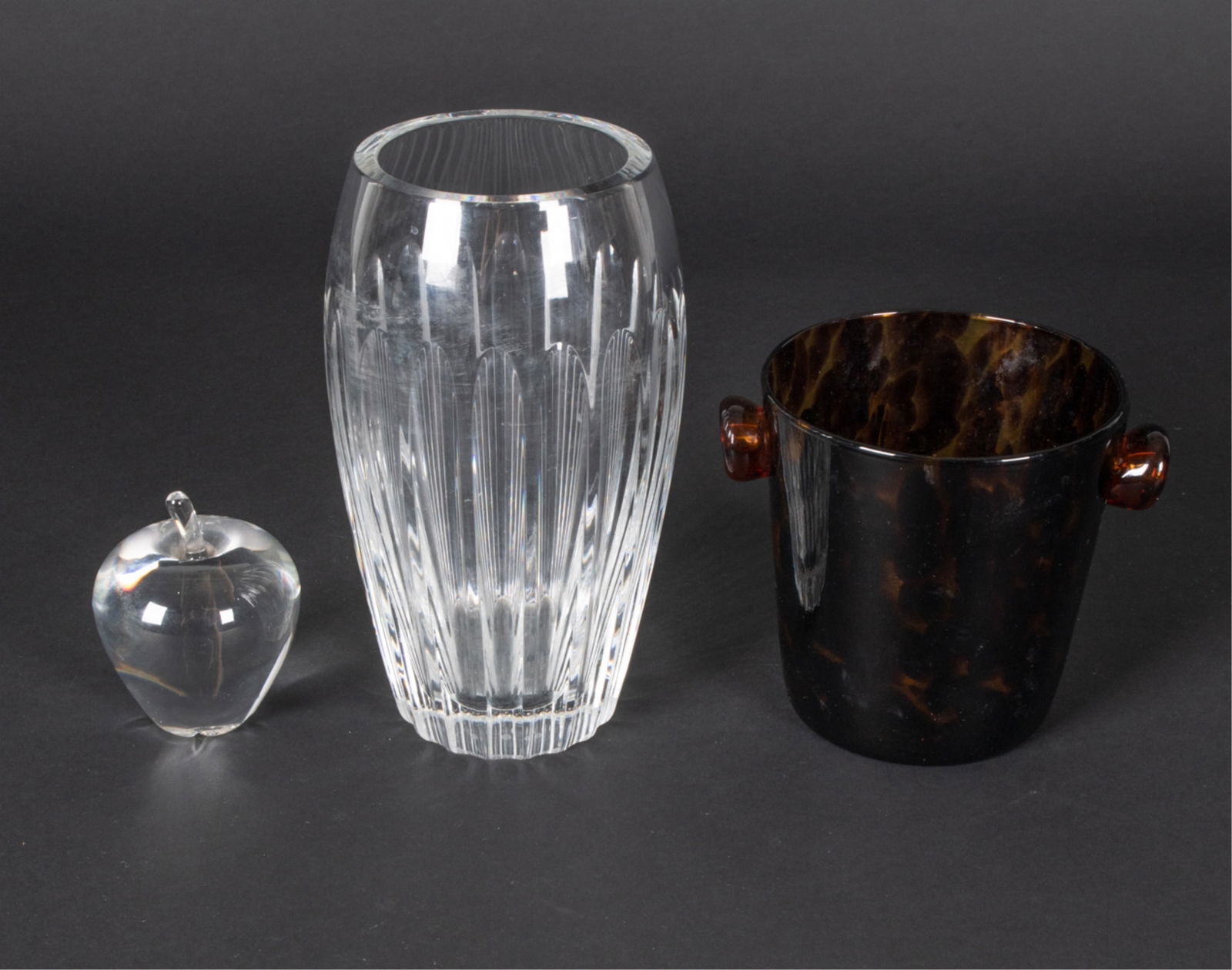 DECORATIVE GROUPING INCL. BACCARAT, STEUBEN: Baccarat crystal vase, Steuben apple paperweight, and tortoiseshell art glass wine cooler/ice bucket. Dimensions: (Baccarat) H 10" x Dia. 5.25" Condition: A few light scuffs; no signs of chips or crac