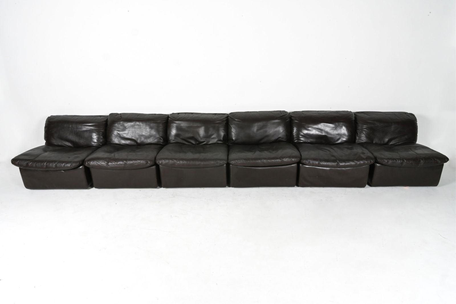 MANNER OF DE SEDE MODULAR LEATHER SEATING SUITE: Leather, steel. modular construction, use alone, in pairs or as a sofa. Dimensions: Each piece H 33" x W 38" x D 40" x SH 15" Condition: Creasing and normal wear to leather consistent with age and use