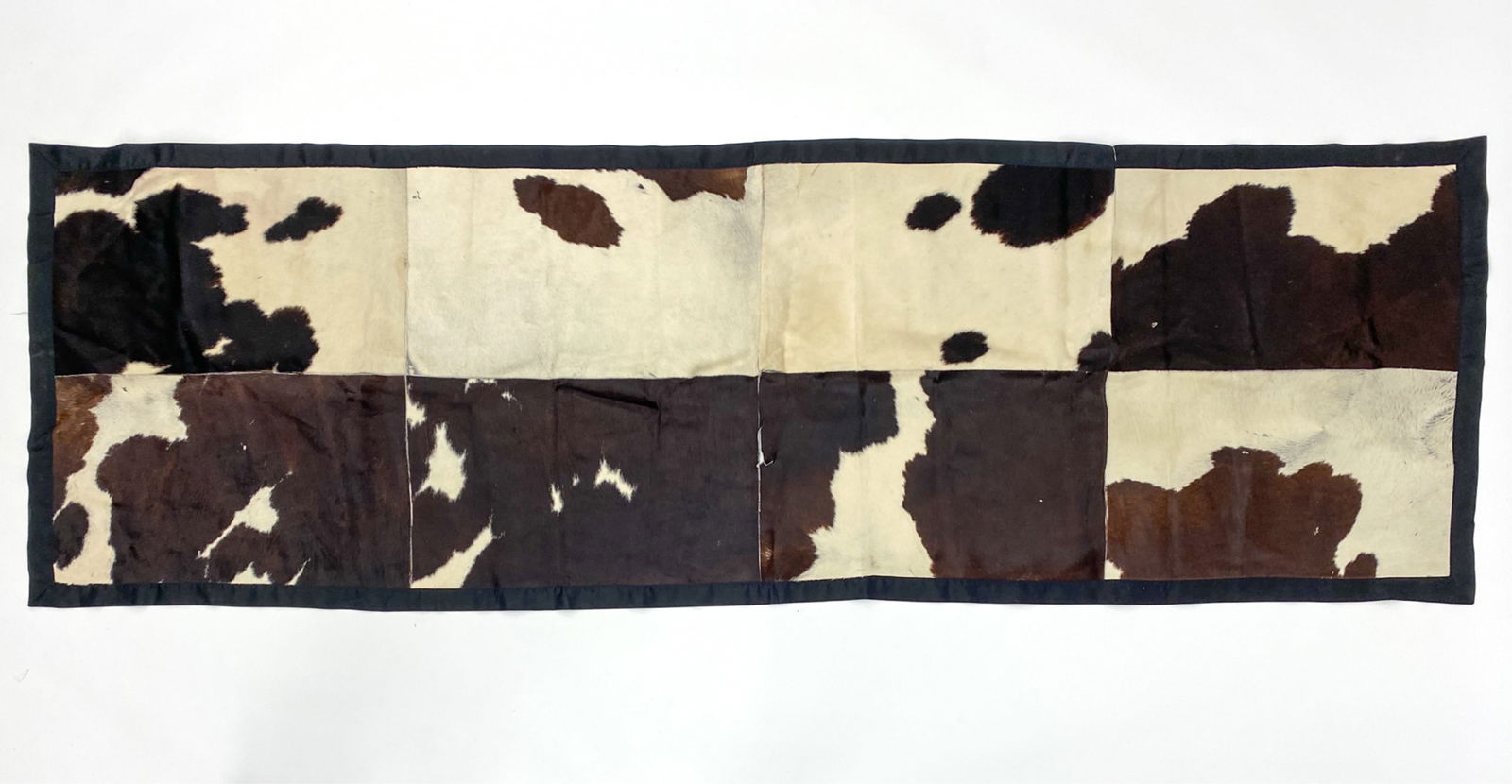ROBERTO CAVALLI CASA PIECED COW HIDE RUNNER RUG: With label to corner underneath. Dimensions: L 118" x W 38" Condition: Some seams separating. Some tears. Some stains, some loss of hair.
