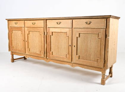 SCANDINAVIAN OAK SIDEBOARD, C. 1970'S: Scandinavian Brutalist oak sideboard in the manner of Henning Kjaernulf, with traditional moldings and carved details, c. 1970's. Key included.Dimensions: H 34.5" x W 79.5" x D 17.75"Condition: Wood w