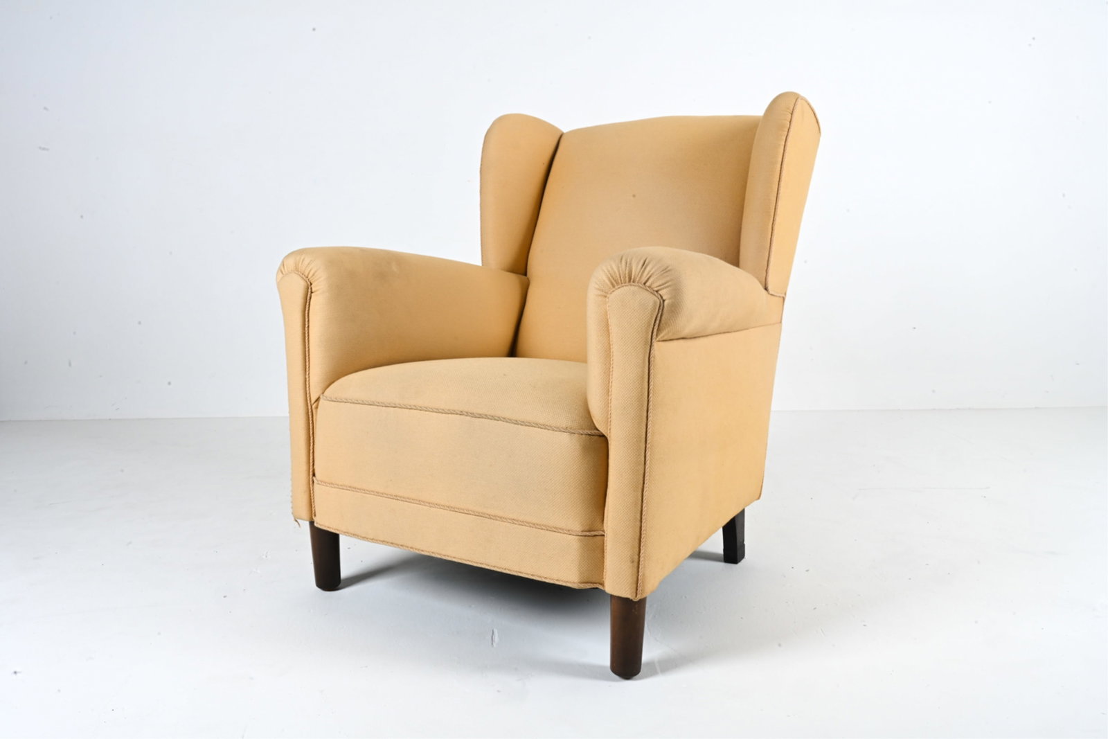 DANISH 1950'S WINGBACK EASY CHAIR: With beech legs, finished in dark stain. Dimensions: H 37.5" x W 33" x D 38" x SH 16.25" Condition: Fabric with sun fading, a few spots of soiling and a couple small pulls. A few scuffs and water spot