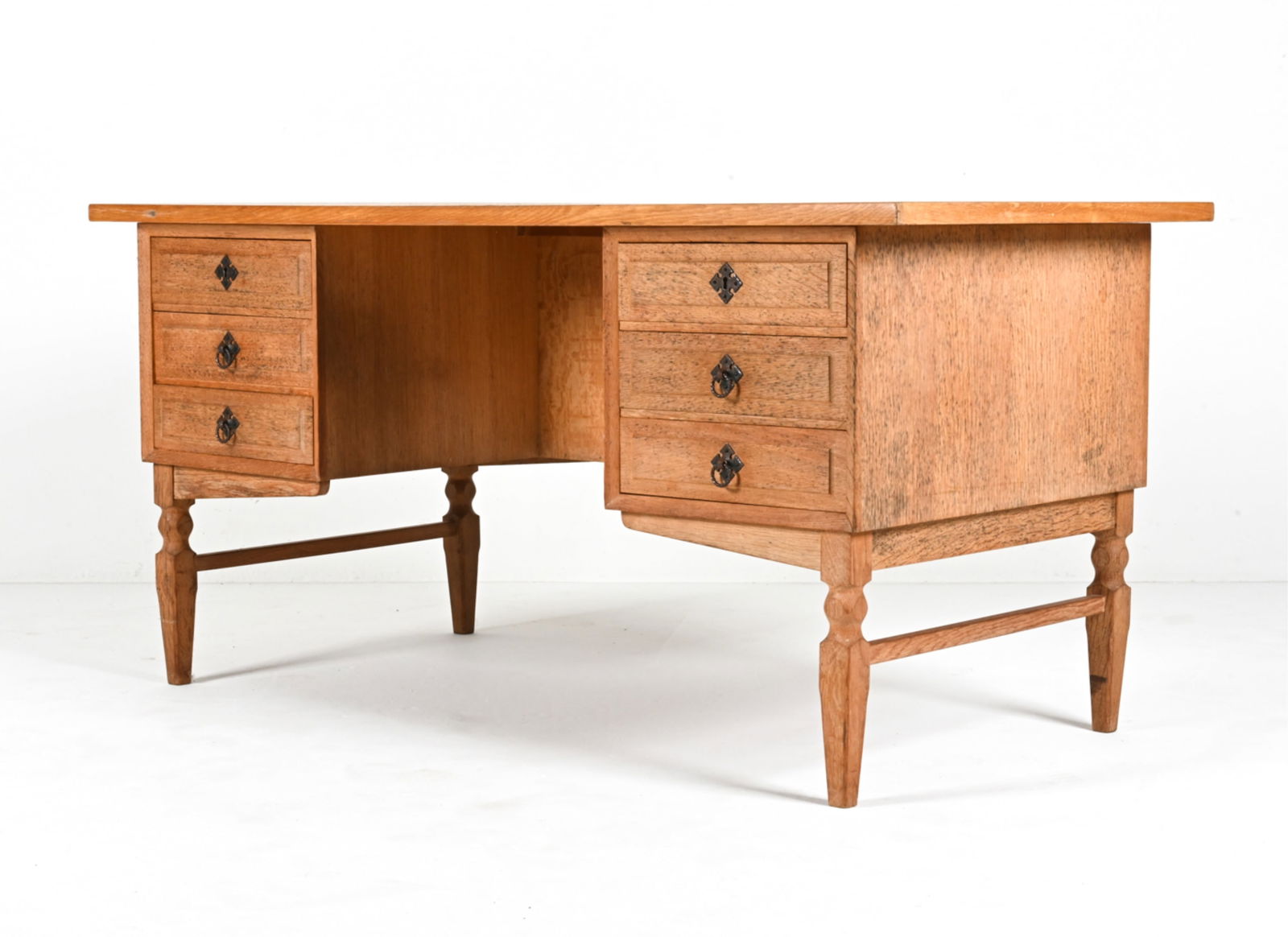 ATTR. HENNING KJAERNULF OAK EXECUTIVE DESK: Scandinavian Brutalist desk in white oak, featuring dovetailed drawers, sculpted legs and Medieval-inspired hardware. Attributed to Henning Kjaernulf, c. 1970's. Key included. Dimensions: H 29" x W 59