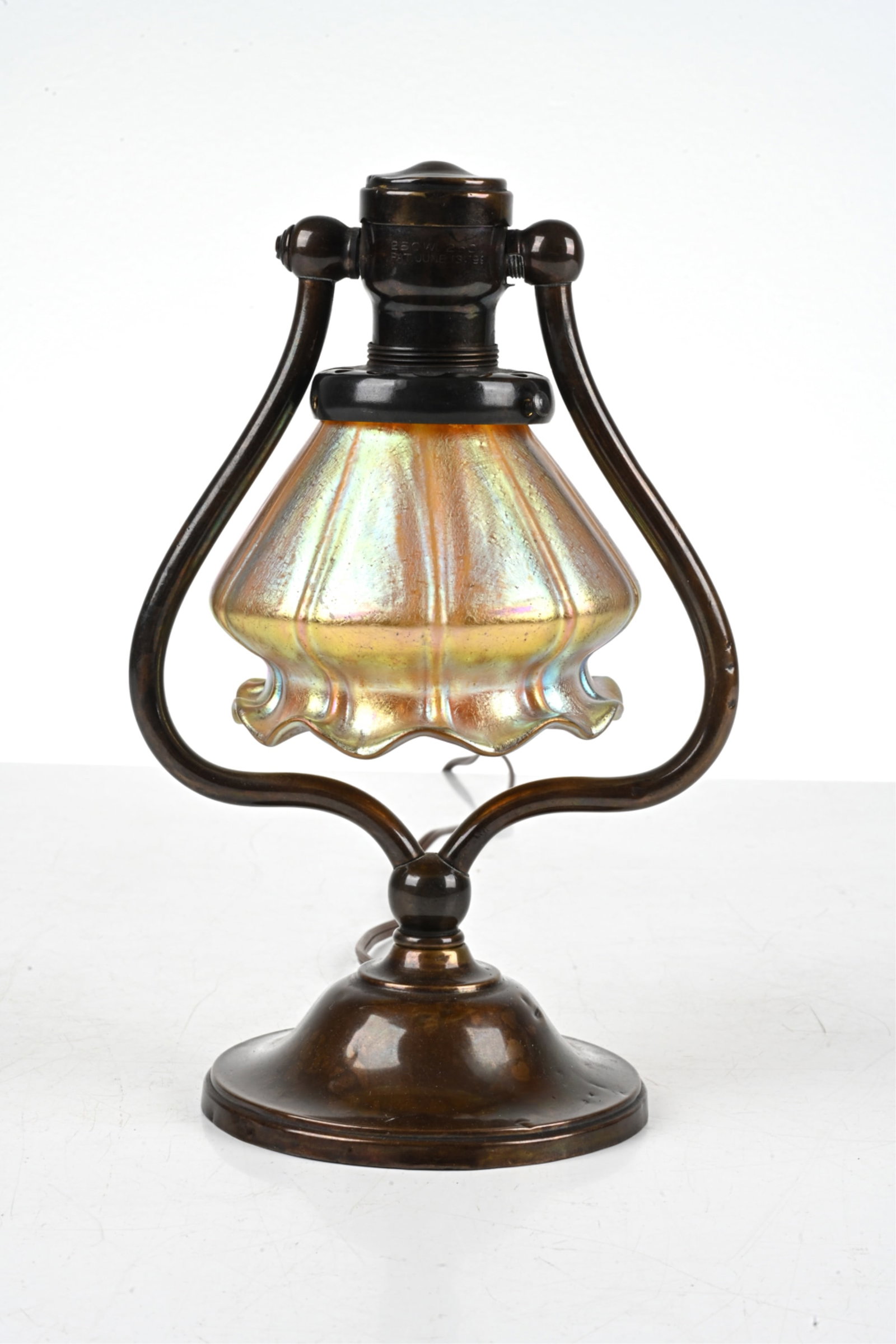 TIFFANY-STYLE IRIDESCENT GLASS HARP LAMP: Early 20th Century. Dimensions: H 11.5" x W 6.5" x D 5" Condition: Wiring not tested. Shade fitter missing one screw. Natural patination, a few small dings to metal at base. Light wear consistent with