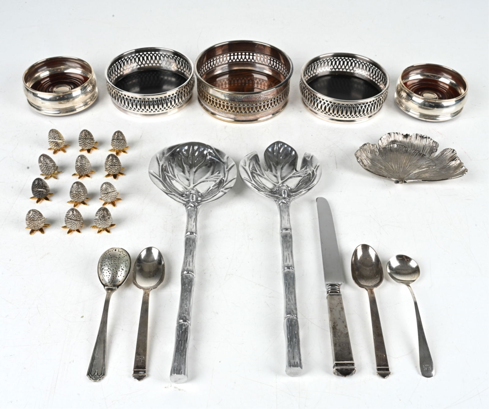 GROUPING OF DECORATIVE TABLEWARE INCL. STERLING: Includes: (10) strawberry-form placecard holders, several sterling silver spoons, sterling- and silverplate-mounted wine coasters, and various others. Dimensions: (Largest, salad server) L 12.5" x W 4