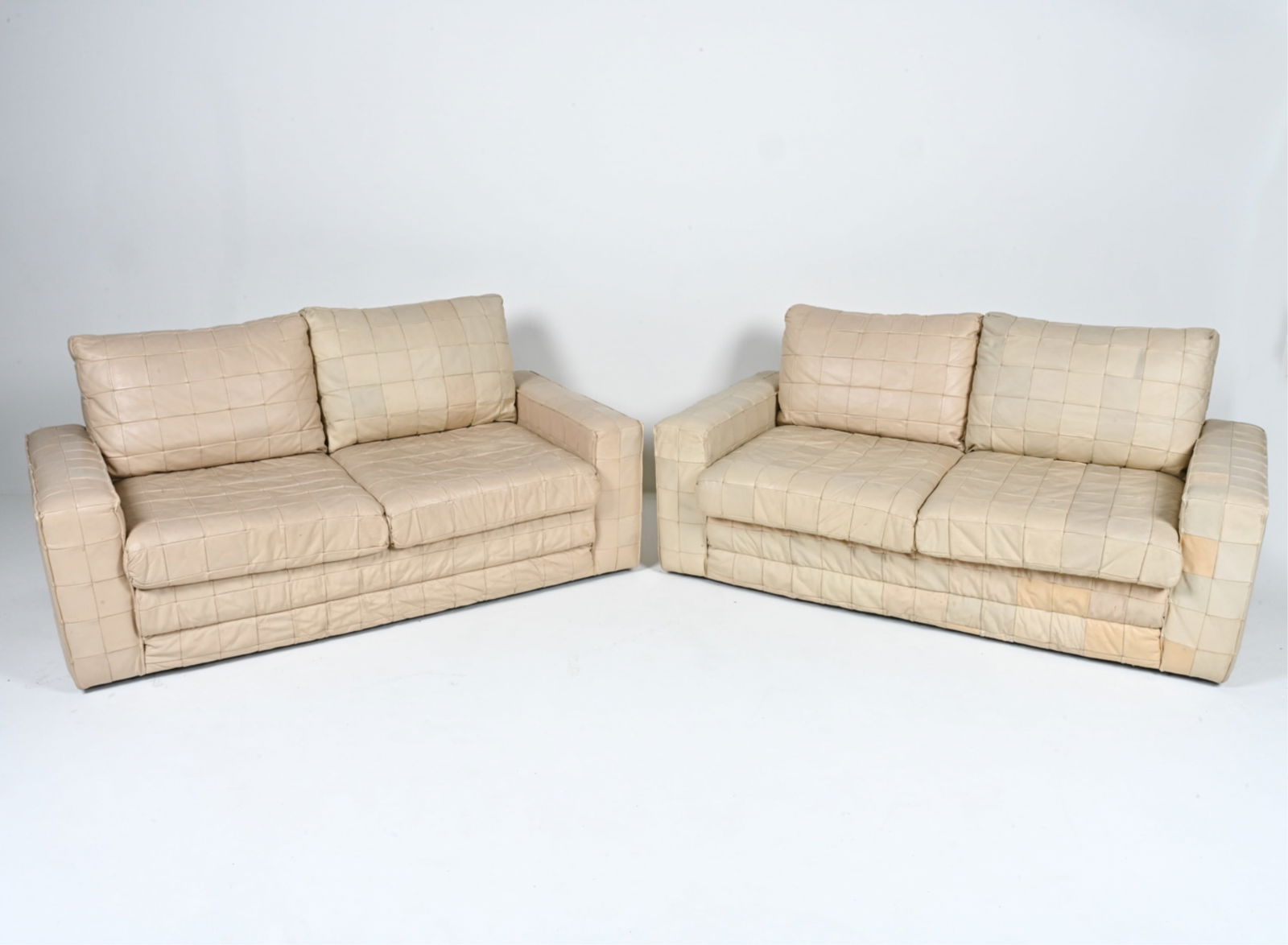 PAIR OF PATCHWORK LEATHER DE SEDE-STYLE SOFAS: Pair of two-seat sofas in cream patchwork leather; c. 1970's. Dimensions: H 31" x W 64.5" x D 36" x SH 15.5" Condition: Sofas present well overall. Leather with natural patination and wear consistent