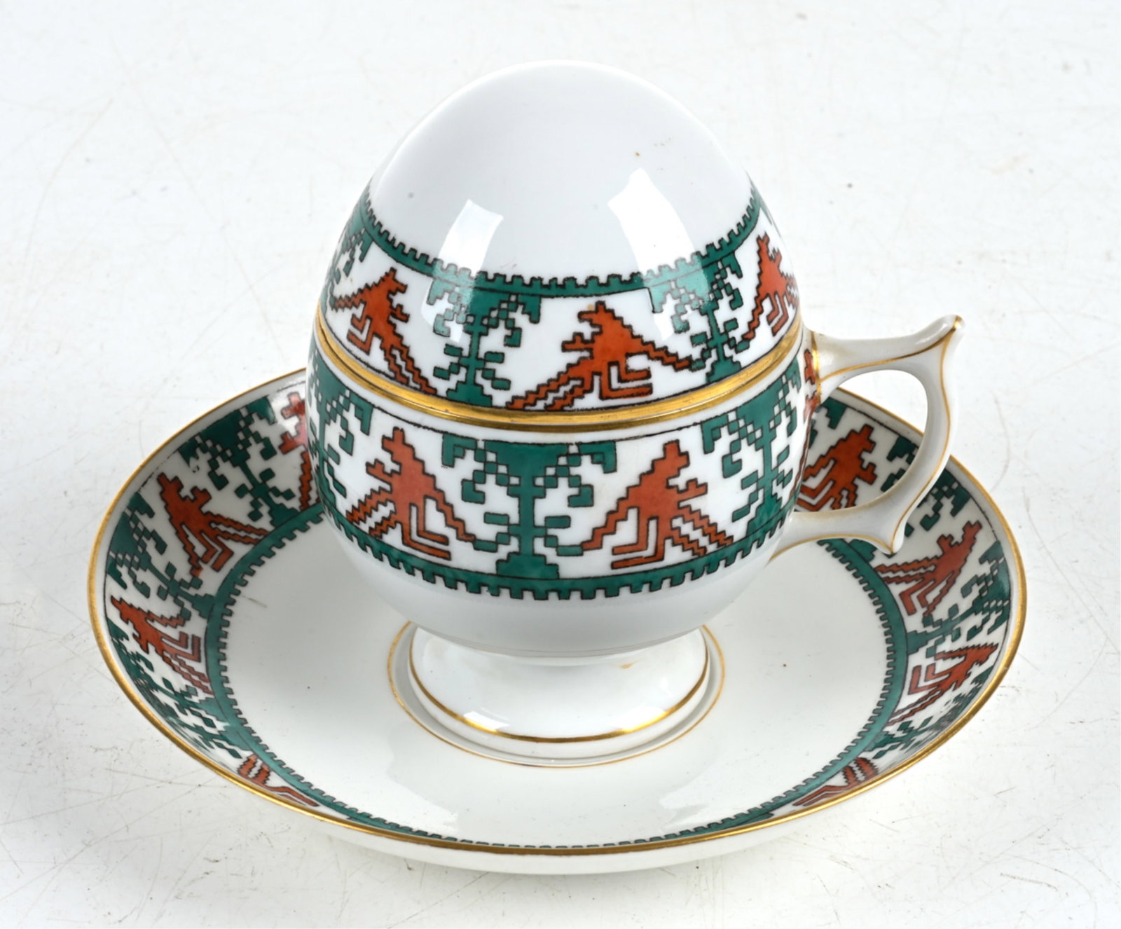 KORNILOV BROS. RUSSIAN PORCELAIN EGG-FORM TEACUP: C. Early 20th Century; marked underneath. Dimensions: (Cup, with lid) H 4" x W 4" x D 3.25" ; Saucer measures 5.75" in diameter. Condition: A few light rubs to decoration; no signs of chips, cracks, o