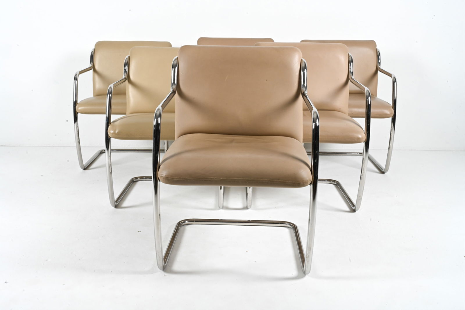 (6) JOHN DUFFY FOR BRUETON TUBULAR CHROME CHAIRS: An exceptional set of (6) "Duffy" dining chairs, featuring cantilevered tubular chrome bases and tan leatherette upholstery. Designed by John Duffy for Brueton, c. Late 20th Century. One chair labeled