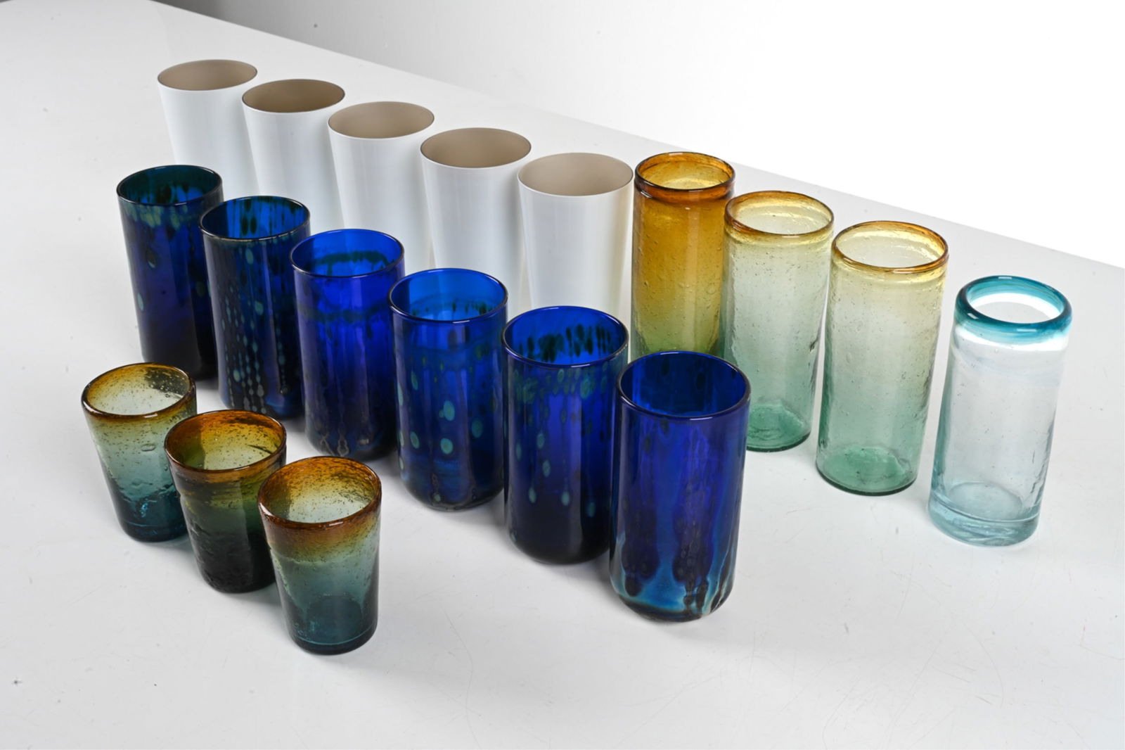 GROUPING OF HANDMADE STUDIO GLASS TUMBLERS: Possibly including Murano. Dimensions: (Tallest) H 6.5" x Dia. 2.75" Conditions: Grouping presents very well overall. Chips to the rims of (1) small tumbler and (1) tall amber/blue-green tumbler; anot