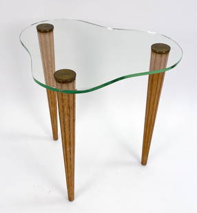 ATTR. T.H. ROBSJOHN GIBBINGS SIDE TABLE: Mid-Century Amoeba free-from glass top side table. Features brass details and sculpted wood legs. Apparently unmarked. Dimensions: H 26.5" x W 27" x D 24" Condition: Minor surface wear, scratches and