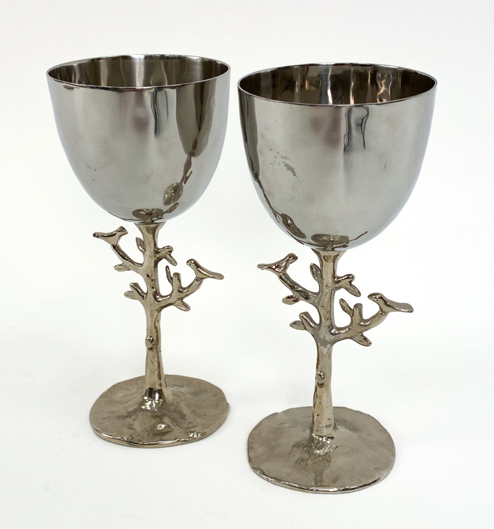 PAIR MICHAEL ARAM KIDDUSH CUP GOBLETS: Stainless steel, nickelplate goblets in botanical form. Distinctly signed Michael Aram. Includes care instructions. Dimensions: H 6.5" x Dia 3" Condition: Very light handling use, including minor mark