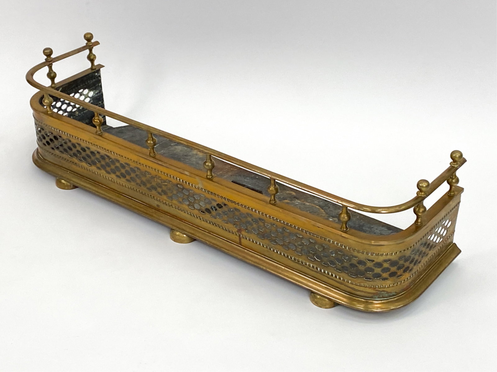BRASS FIRE FENDER: Dimensions: H 11" x W 42" x D 13.5" Condition: Rusting, few loose finials. Surface wear.
