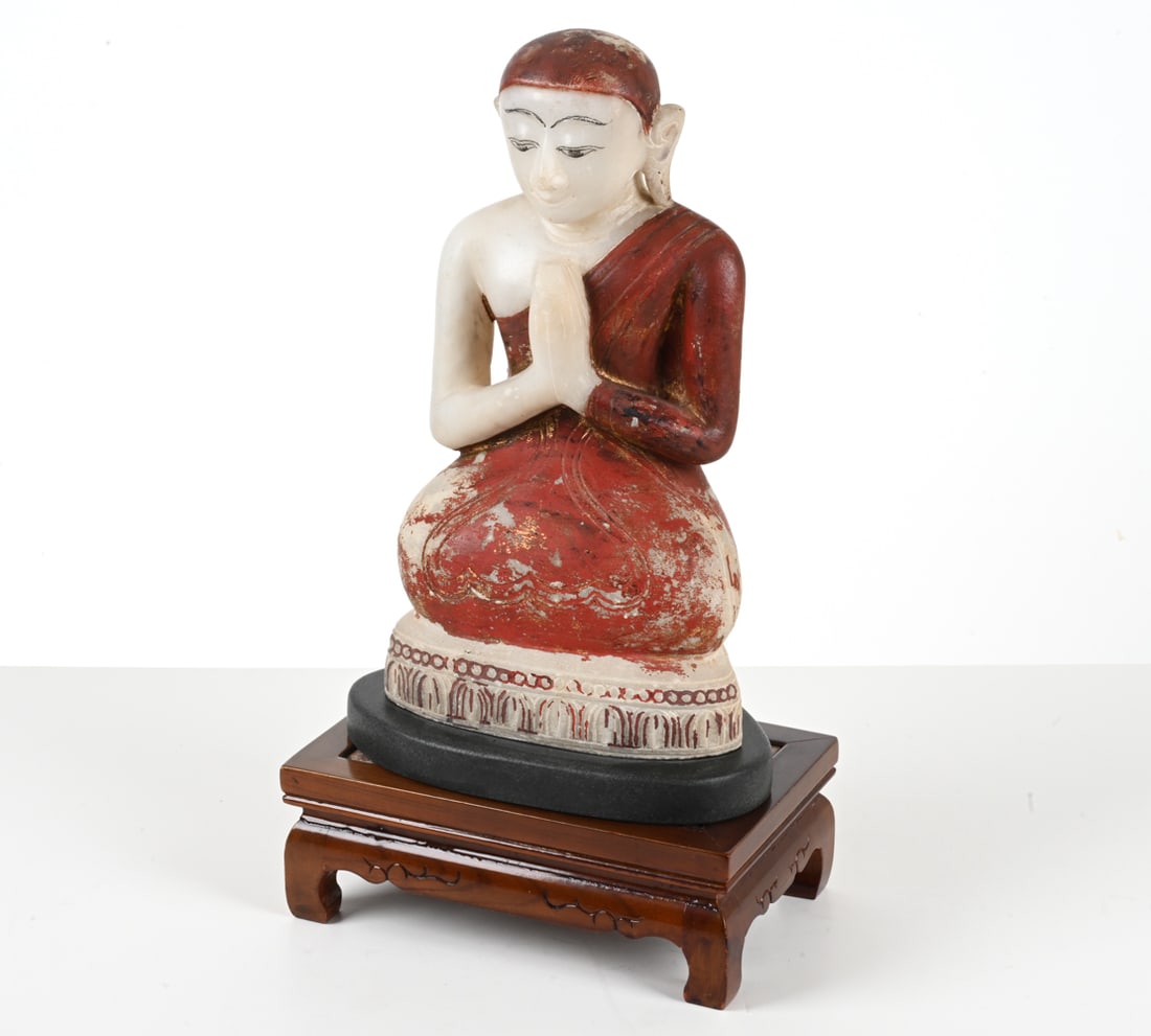 BUDDHIST CARVED & PAINTED ALABASTER STATUE: Buddhist disciple or monk; likely Burmese. Presented on a wood plinth with inset pink marble top. Dimensions: (Including pedestal) H 21" x W 11" x D 7" ; (Statue) H 17.5" x W 10" x D 6.75" Condition:
