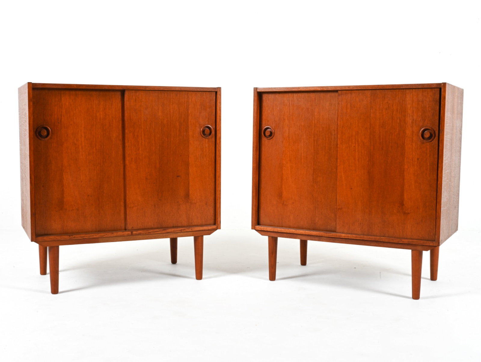 PAIR OF DANISH MID-CENTURY TEAK CABINETS: With adjustable shelves, sliding doors and sculpted bullseye-style handles; c. 1960's-1970's. Dimension: H 33" x W 31.5" x D 17.25" Condition: Scattered dings and scuffs, a few small spots of soiling;
