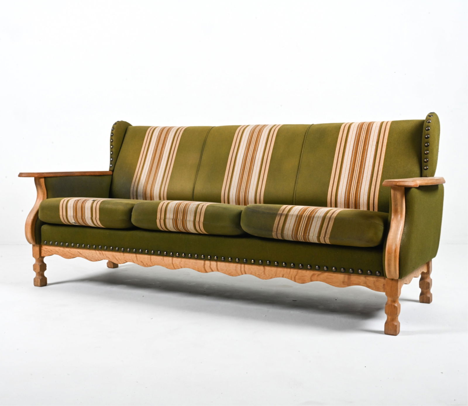 MANNER OF HENNING KJAERNULF OAK SOFA: Scandinavian, c. 1970's. Dimensions: H 31" x W 73" x D 31" x SH 16.5" Condition: Slight musty smell; cleaning recommended. Light rubbing to the cushion fabric, spots of soiling and sun fading. Wear co