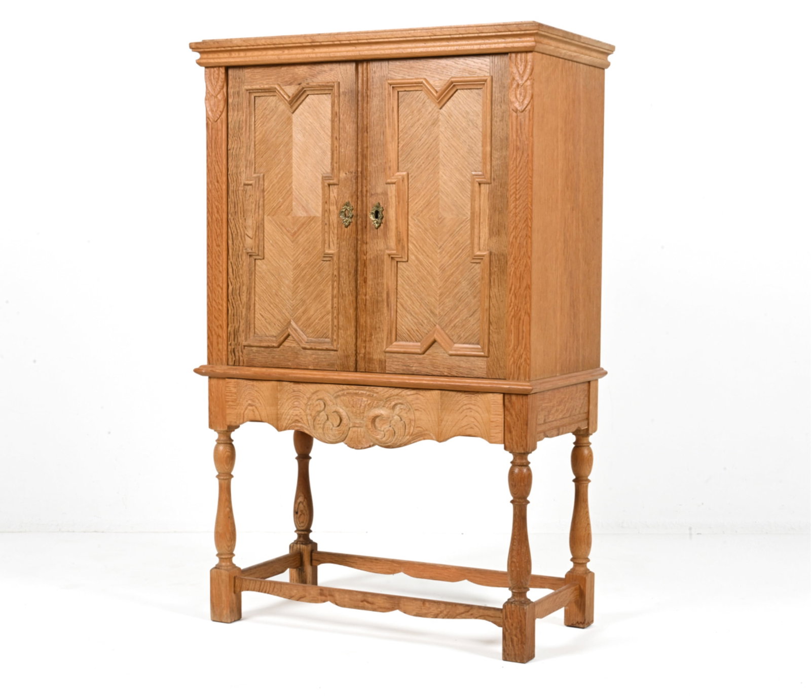 HENNING KJAERNULF OAK DRY BAR CABINET: Beautiful dry bar in quarter-sawn oak; featuring Gothic-inspired recessed panel molding at the doors, carved with stylized leaves at the trim and a scrolled fan or sheaf of wheat motif at the lower "h