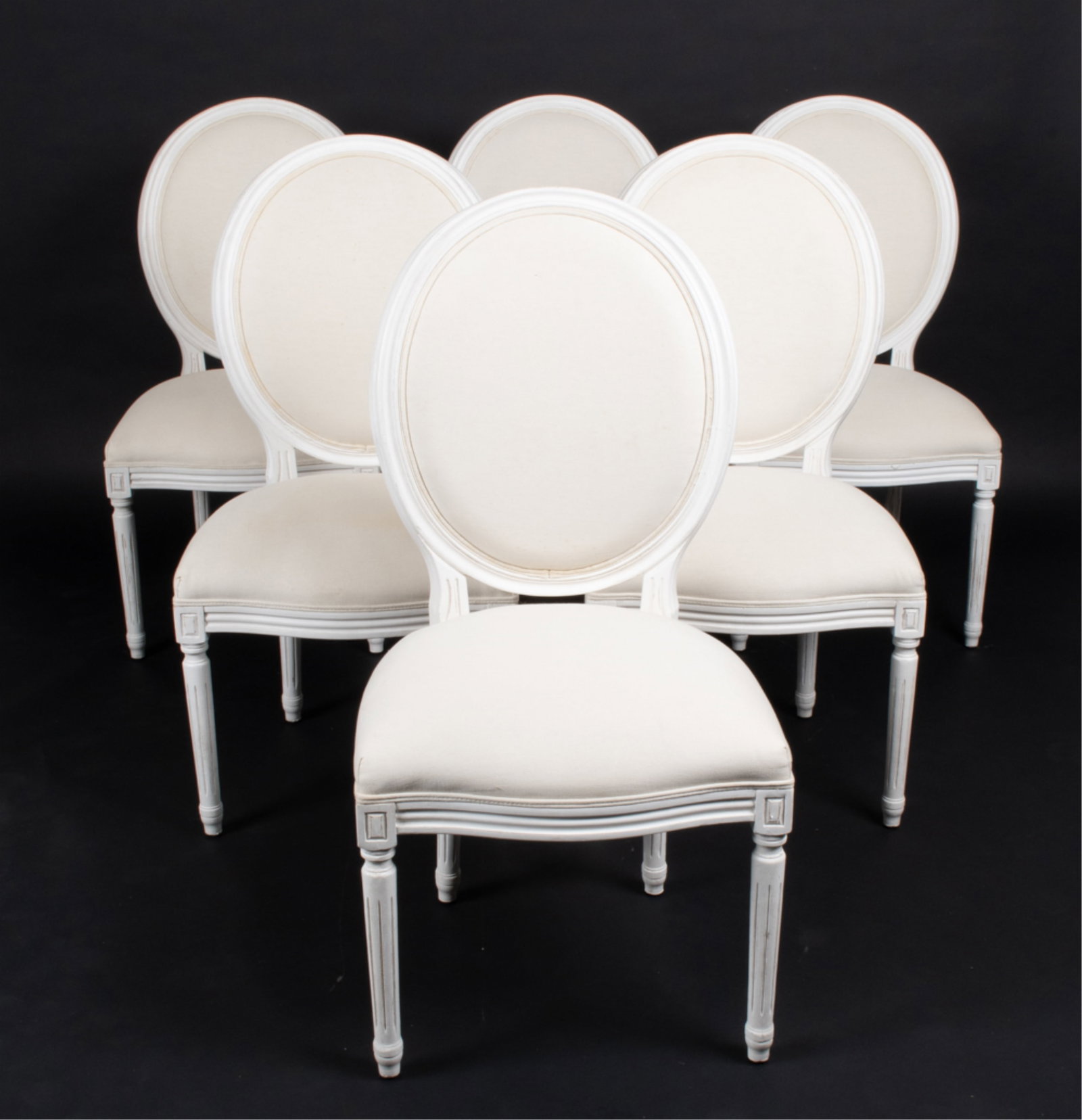 (6) LOUIS XVI-STYLE FAUTEUIL DINING CHAIRS: Contemporary. Finished in white paint and canvas fabric. Dimensions: H 41.25" x W 21" x D 21" x SH 18.5" Condition: Intentionally distressed paint finish, with a few additional dings and scuffs to fra