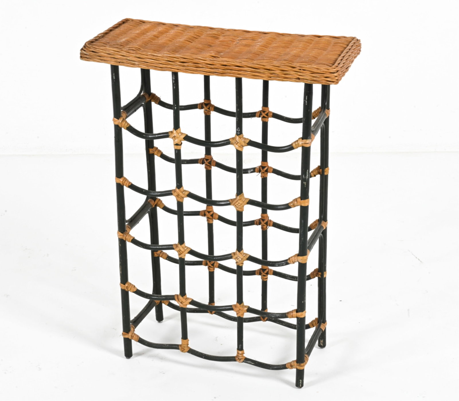 MID-CENTURY DUTCH RATTAN WINE RACK: Ebonized pole rattan and rattan wicker. Dutch.. Dimensions: H 28.75" x W 20.5" x D 10.25". Condition: A few breaks to rattan strapping and wicker top. Finish losses and spots of soiling to pole rattan