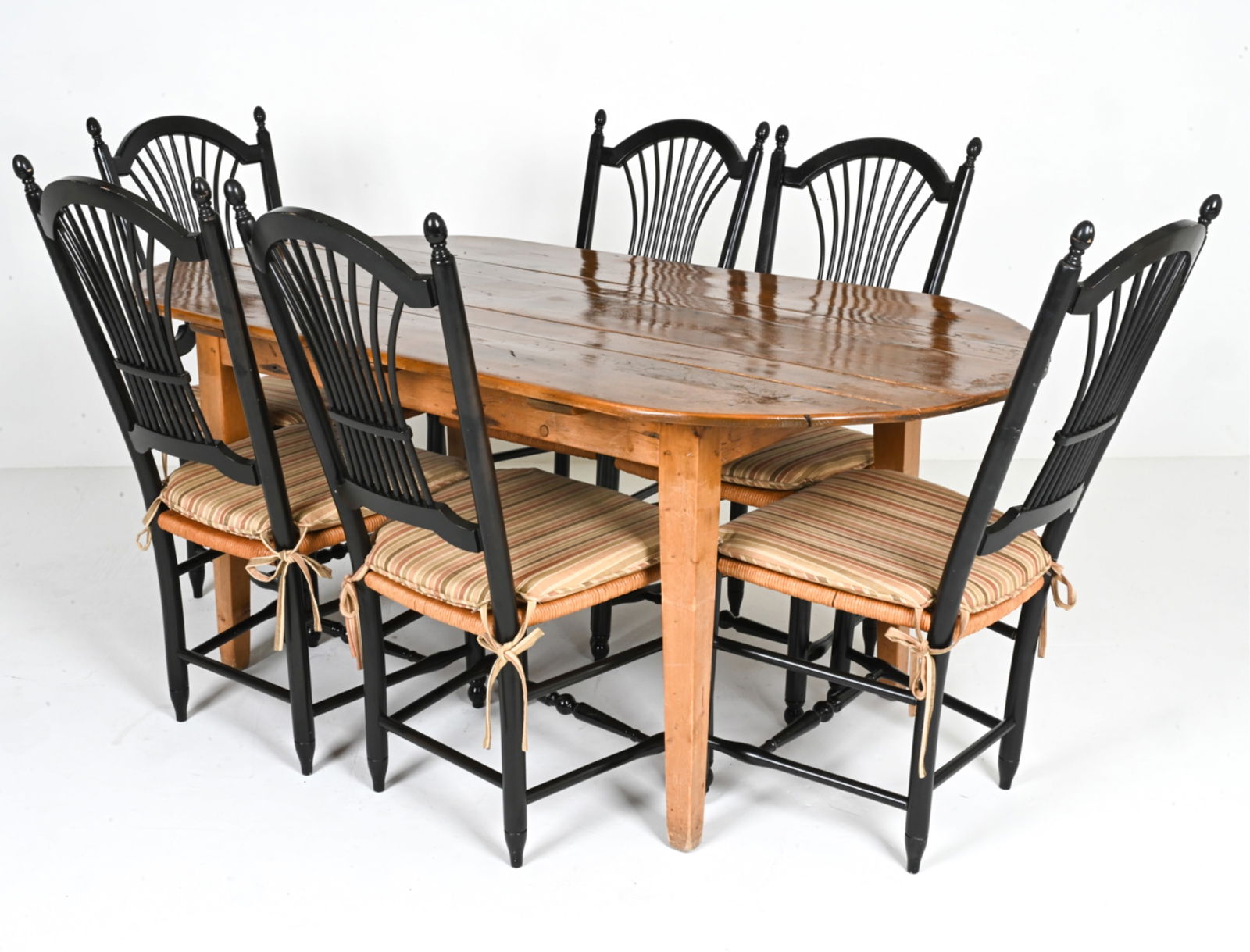 RUSTIC PINE DINING TABLE & (6) SHEAF-BACK CHAIRS: Dining table with oval top crafted from reclaimed antique pine wood; paired with (6) ebonized side chairs featuring papercord rush seats and sheaf backs. One chair labeled Nichols & Stone Co. undernea
