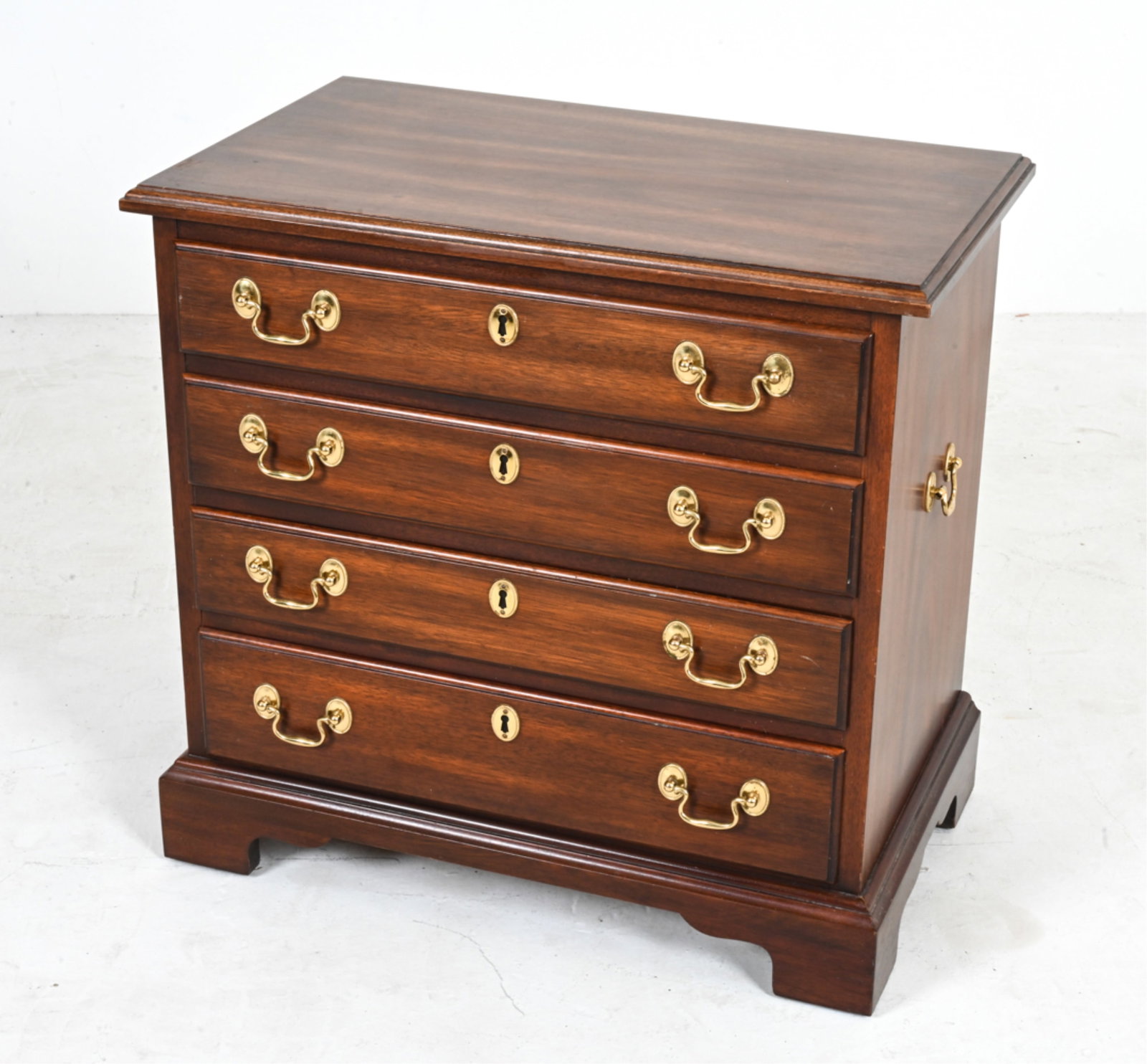 HENKEL-HARRIS MAHOGANY SIDE CHEST: Vintage Henkel-Harris diminutive chest with 4 drawers. Mahogany with brass pulls. Heat-stamped inside drawer. Circa 1970's. Dimensions: H 23" x W 24" x D 14.5". Condition: Sun fading to top; scattered