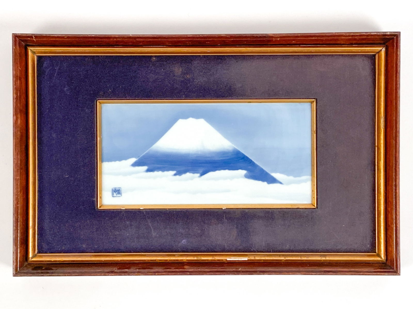 JAPANESE PORCELAIN MOMOYAMA TILE: Tile in blues and white, mount Fuji. Markings lower left corner. Inscription verso. Dimensions: (Frame) H 13.25" x W 21" (Sight) H 6" x W 11.75" Condition: Tile clean. Damages to frame.