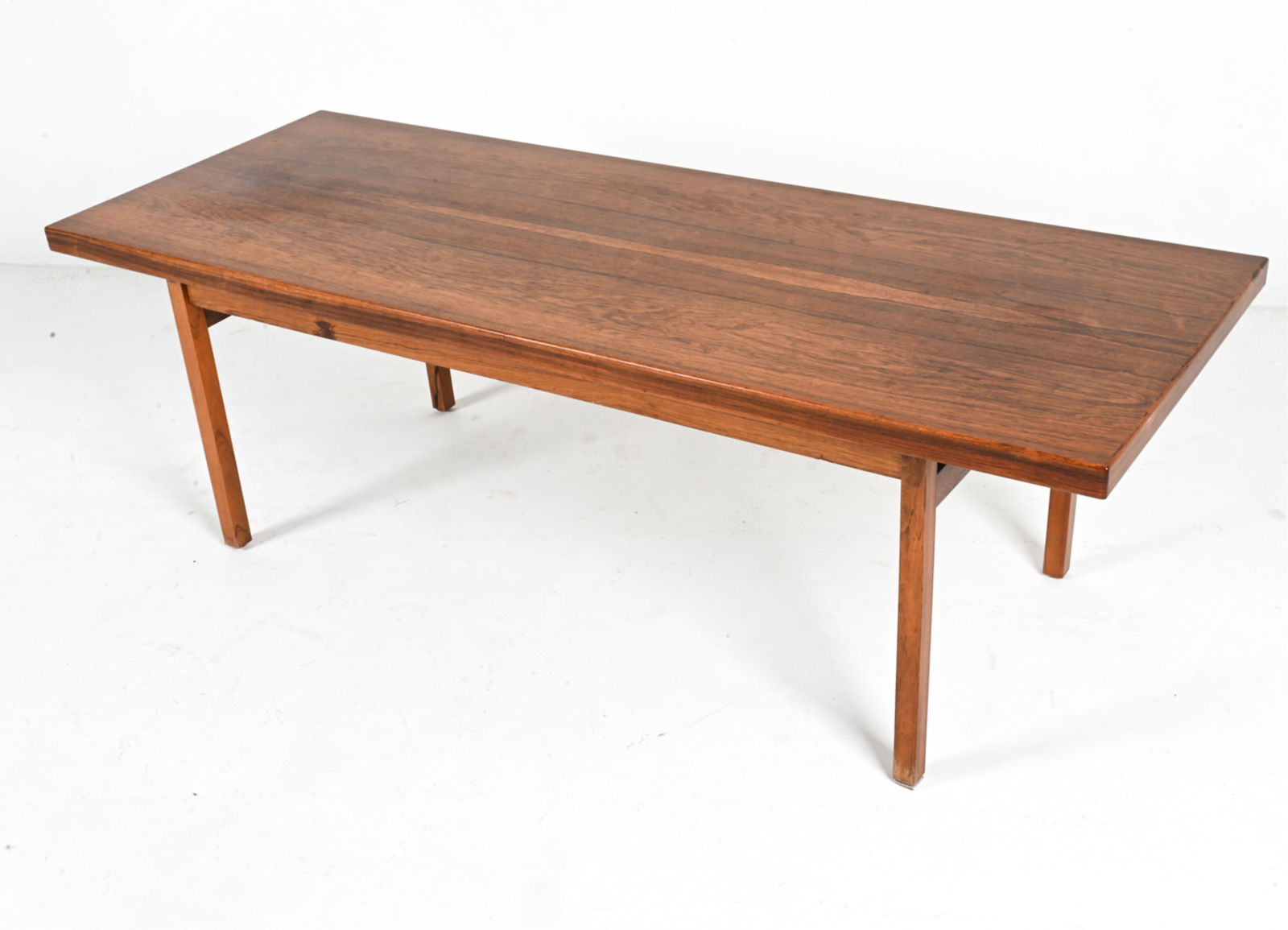 MANNER OF ILLUM WIKKELSO ROSEWOOD COFFEE TABLE: Mid-Century Minimalist rosewood coffee table in the style of Illum Wikkelso's "Capella" series for Niels Eilersen. Stamped "O.L. No. 62-" underneath. Denmark, c. 1960's. Dimensions: H 20" x W 62" x D