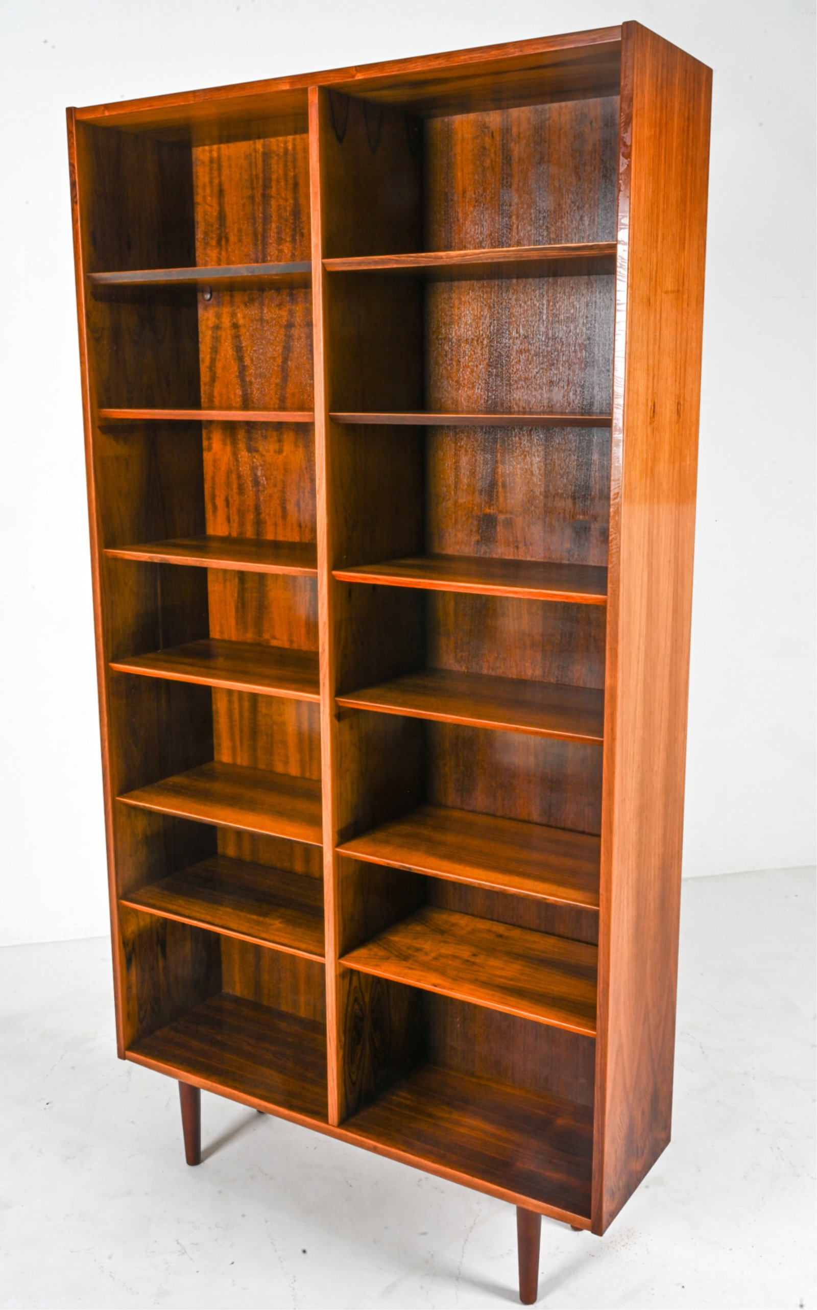 POUL HUNDEVAD DANISH ROSEWOOD TALL BOOKCASE: Tall bookcase in rosewood, with tapered legs and adjustable shelves. Designed by Poul Hundevad for Hundevad & Co.; with original label on back panel. Denmark, c. 1960's. Dimensions: H 80.75" x W 42.5"