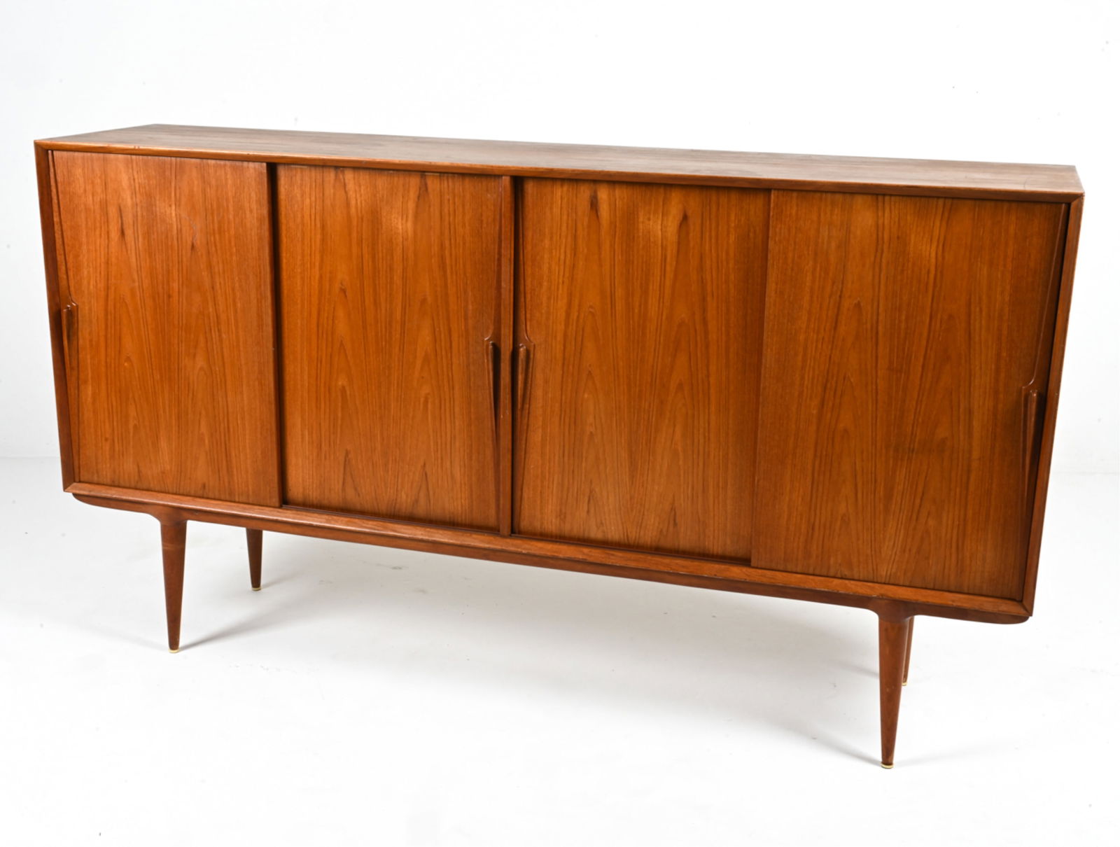 GUNNI OMANN FOR OMANN JUN TEAK SIDEBOARD: Rare Danish Mid-Century sideboard in teak, featuring sculpted dart-style door handles and adjustable interior shelves. Designed by Gunni Omann for Omann Jun. Label remnant to bottom edge of back panel