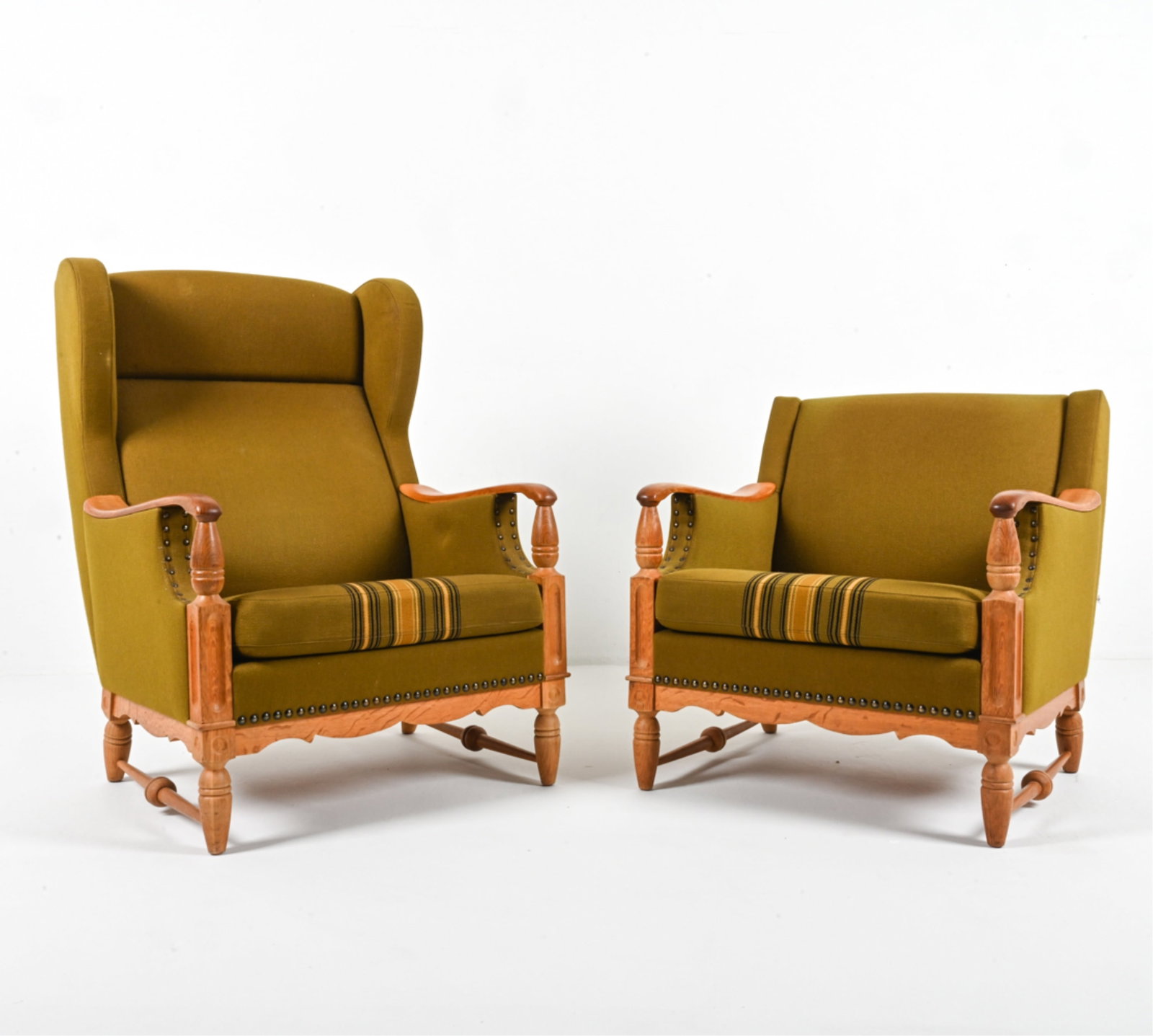 (2) ATTR. HENNING KJAERNULF OAK LOUNGE CHAIRS: "His and Hers" style chairs in oak and traditional woven fabric, with traditional turnings and moldings. Attributed to Henning (Henry) Kjaernulf, Denmark, c. 1960's. Dimensions: (Larger) H 40.5" x W 3