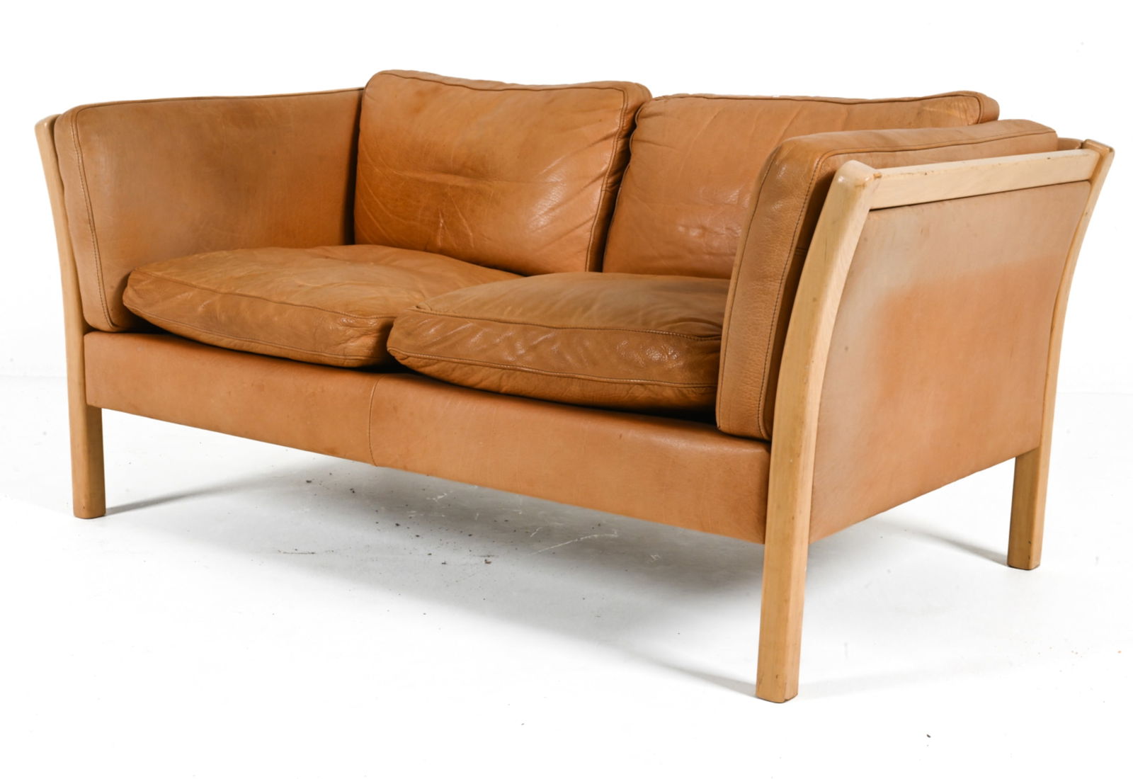 STOUBY DANISH TWO-SEAT SOFA IN BEECH & LEATHER: Lined in Stouby logo fabric. Denmark, c. 1970's. Dimensions: H 28.25" x W 58.25" x D 31.5" x SH 17.25". Condition: Scuffs and scratches on edges of wood, leather patinated from age and use. B017