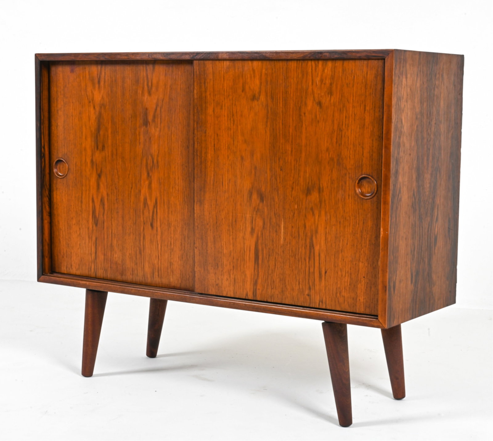 DANISH ROSEWOOD CREDENZA, C. 1960'S: Shelves adjustable. Circular inset pulls on sliding cabinet doors. Danish, circa 1960's. Dimensions: H 28" x W 33.75" x D 12.75". Condition: Small spots of discoloration on top. Small breakage to slid