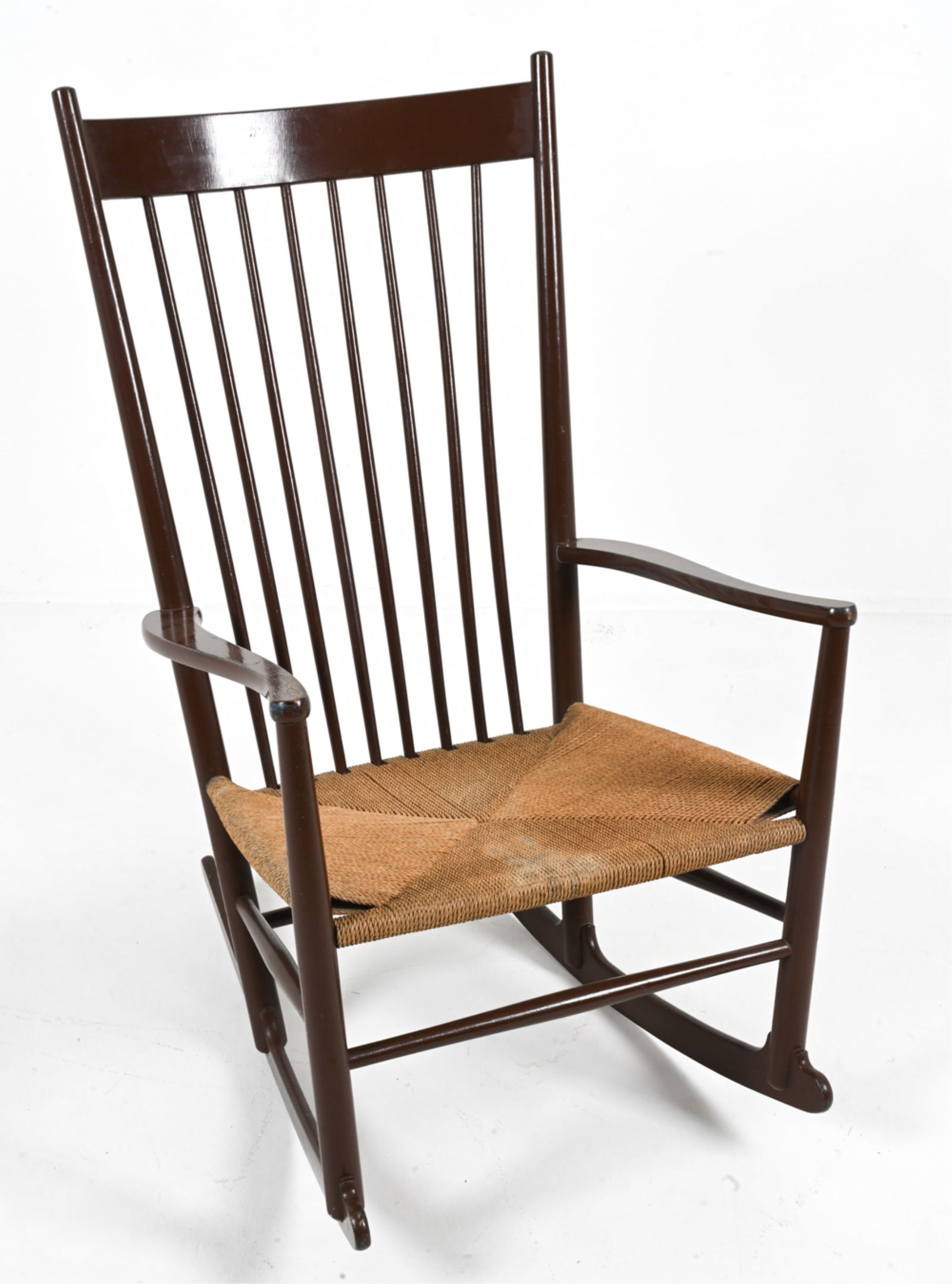 HANS WEGNER FOR FDB MODEL J16 ROCKING CHAIR: Painted brown, with some blue paint visible underneath. Woven paper-cord seat. Produced by FDB Mobler, Denmark. Mid- to Late-20th Century. Dimensions: H 43" x W 25" x D 31" x SH 15". Condition: A few