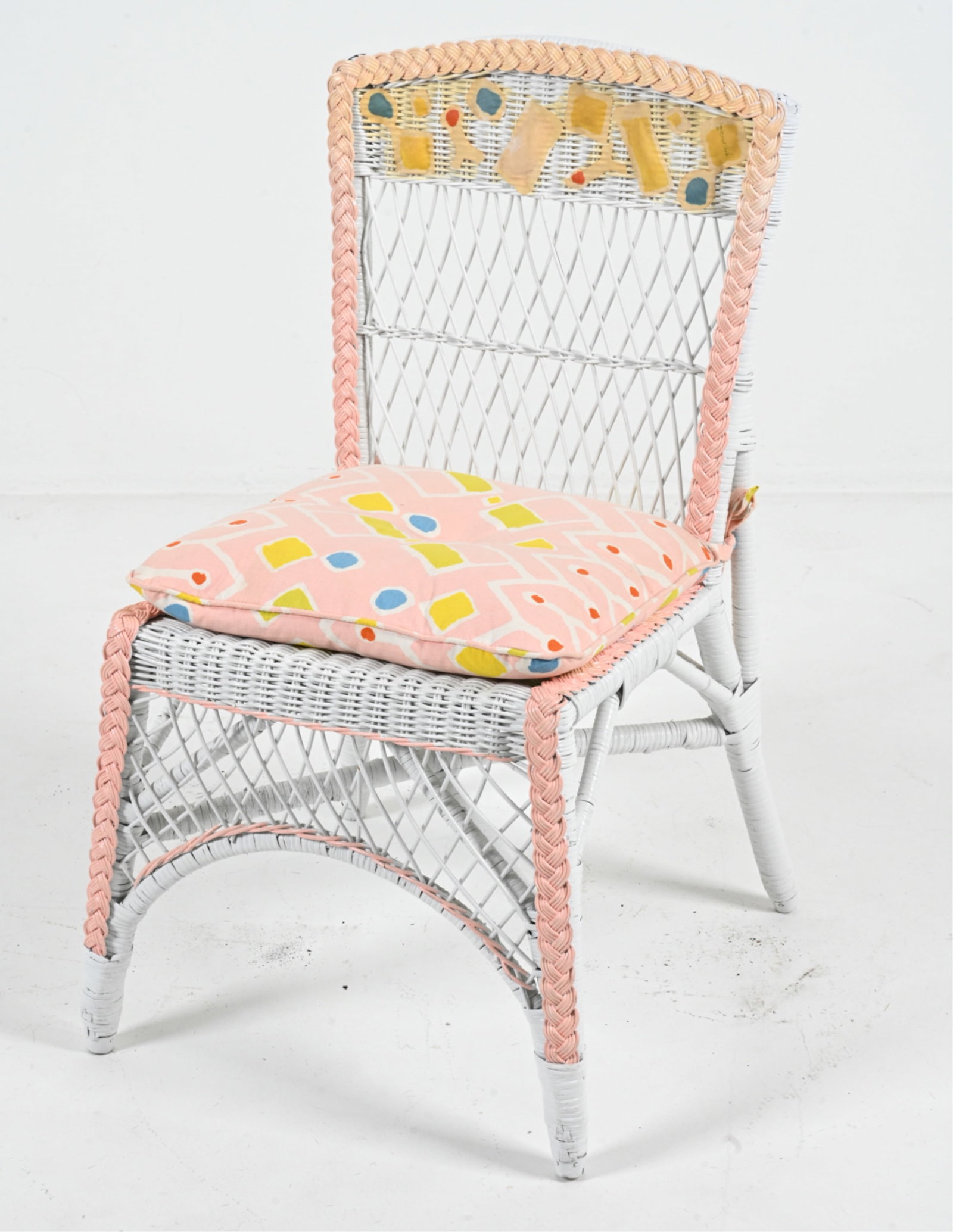 ARTISAN HAND-PAINTED WICKER CHAIR: Signed and dated indistinctly on the backrest. Dimensions: H 33" x W 20" x D 20" x SH 19". Condition: A few small breaks to wicker; a few faint marks to fabric; some toning to fabric applique on backr