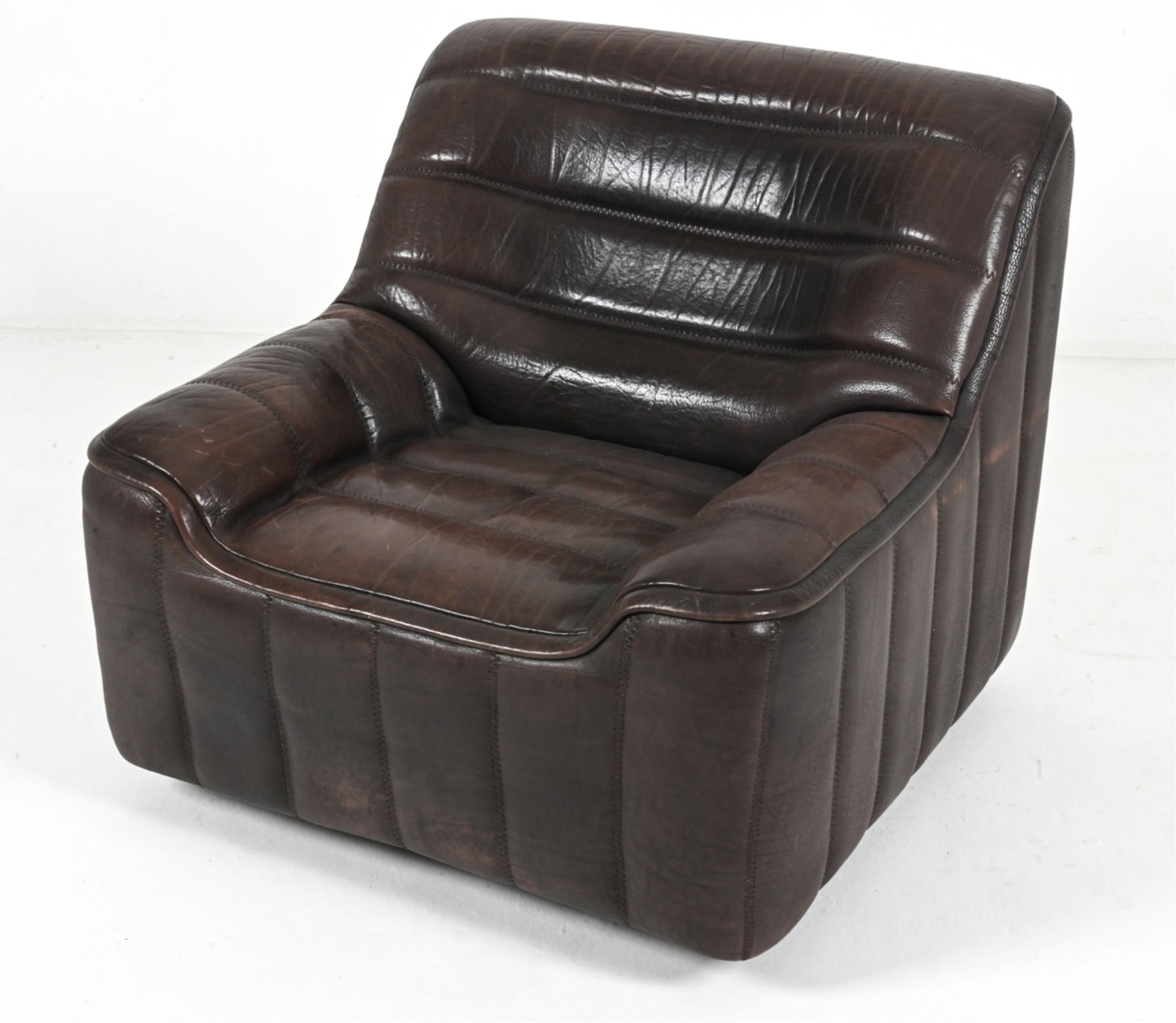 DE SEDE DS-84 BUFFALO LEATHER LOUNGE CHAIR: Luxurious Model DS-84 lounge chair in channel-stitched buffalo leather, produced by De Sede, Switzerland; c. 1970's. Dimensions: H 31.75" x W 35" x D 34" x SH 15" Condition: Rich natural patination; a