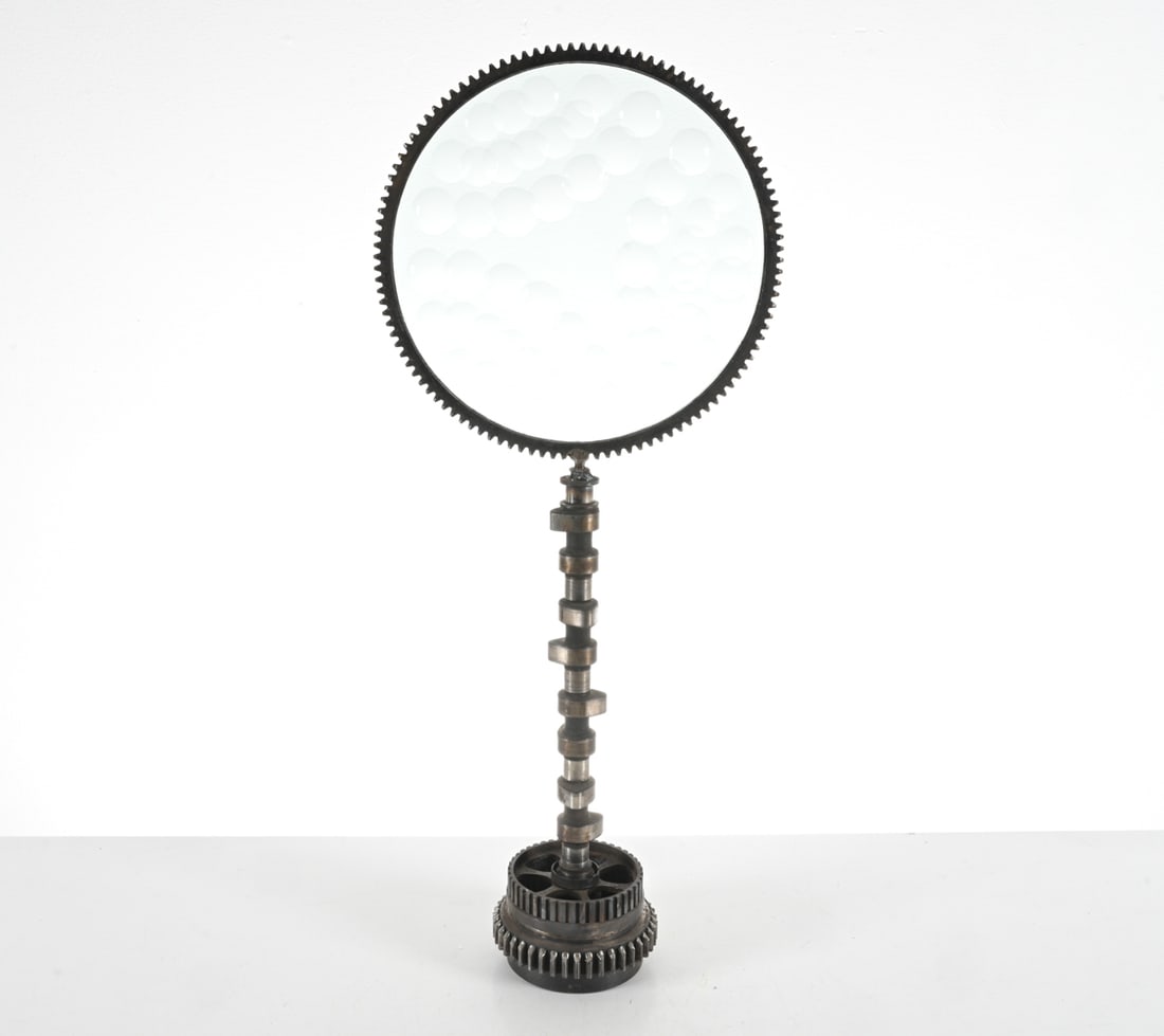 FELICIANO BEJAR (MEXICO/NY, 1920-2007) SCULPTURE: Marked Brazil on metal. Artist signature incised on edge of glass. Steel, iron, and glass Magiscope sculpture with magnified dimples in a cog frame, crankshaft base. Top screws onto base, two separate